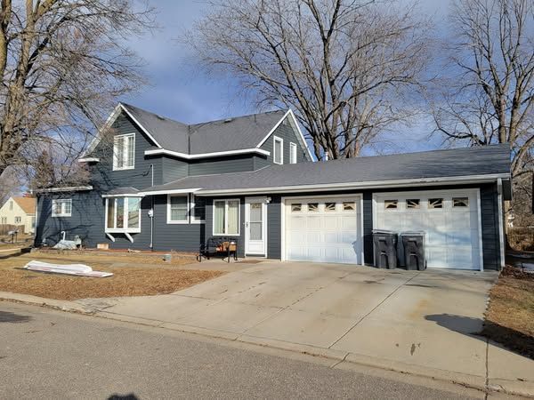 A large house with a garage and a bench in front of it.
