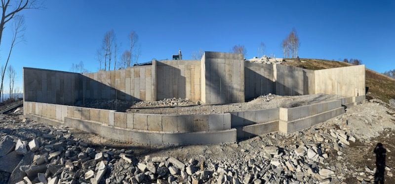 A large building is being built on top of a rocky hill.