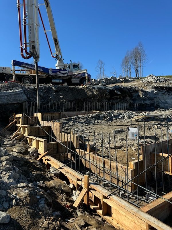 A construction site with a crane pumping concrete into the ground.