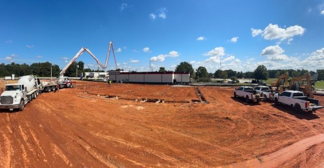 A panoramic view of a construction site with trucks and a crane.