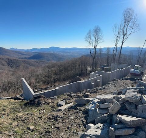 A building is being built on top of a hill with a view of the mountains.
