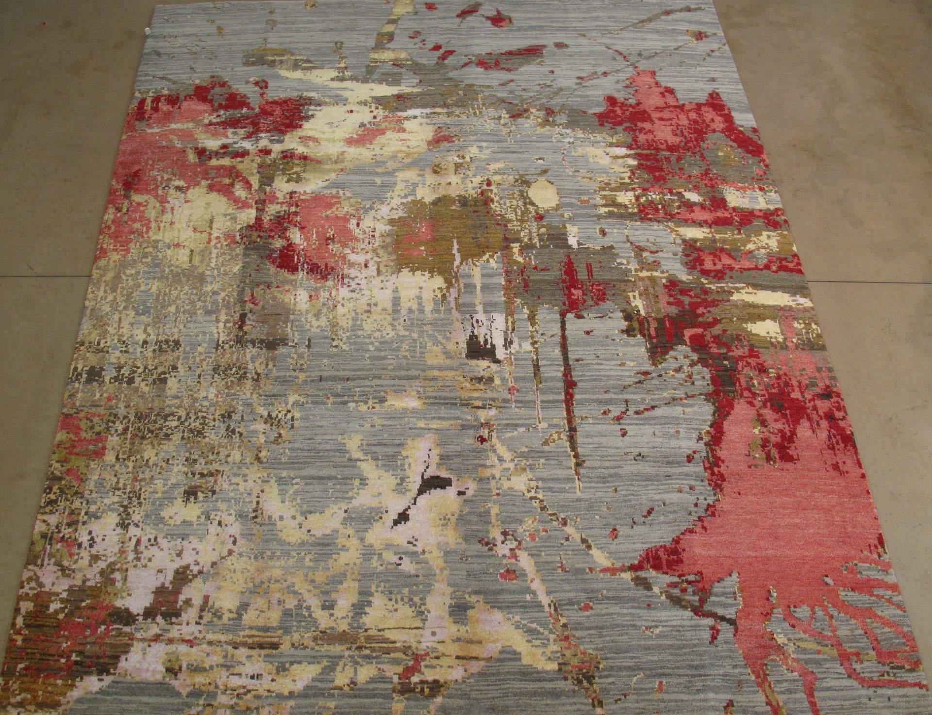 Abstract rug with red, gold, and grey splashes.