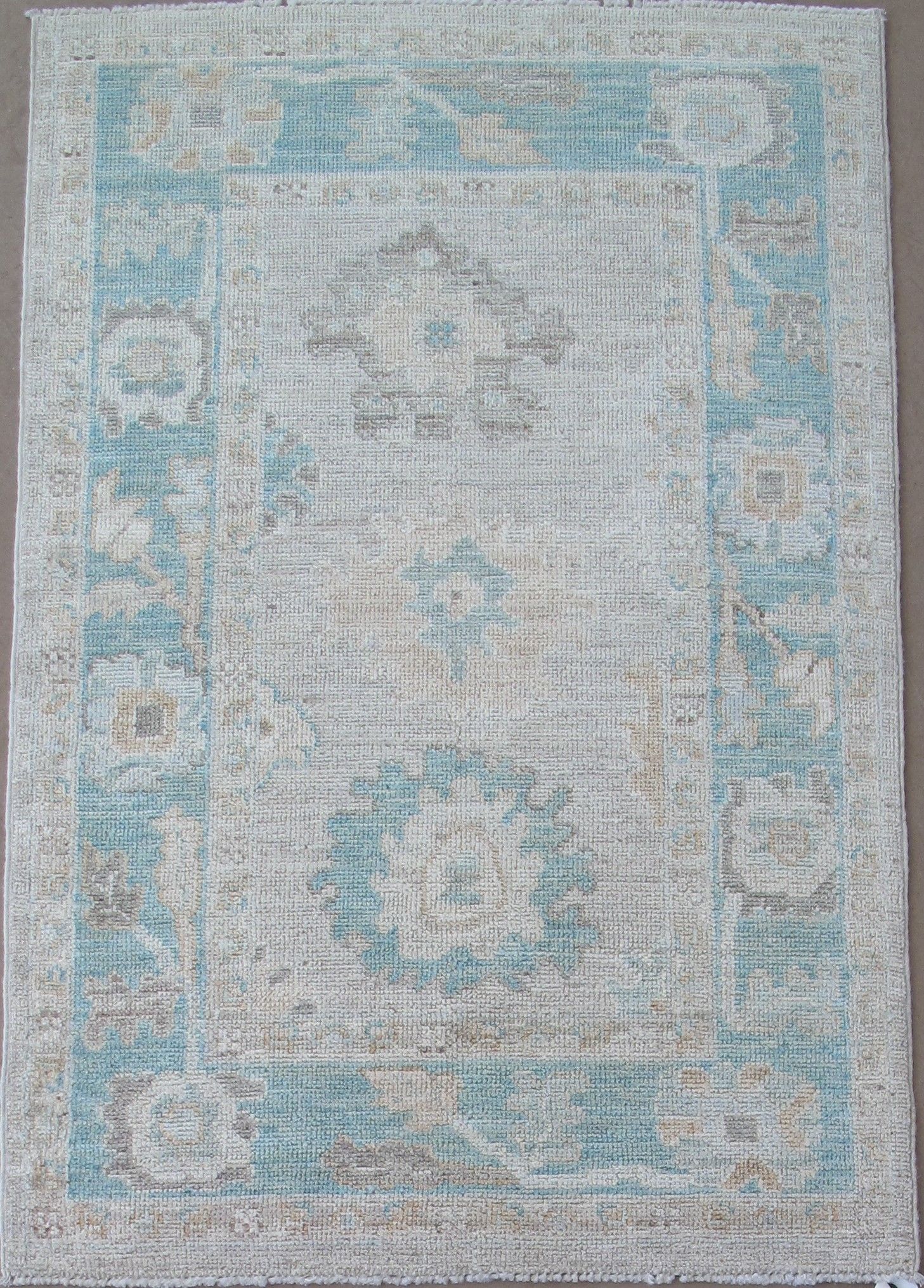 Rectangular rug with a light blue and beige faded design, with a darker blue border.