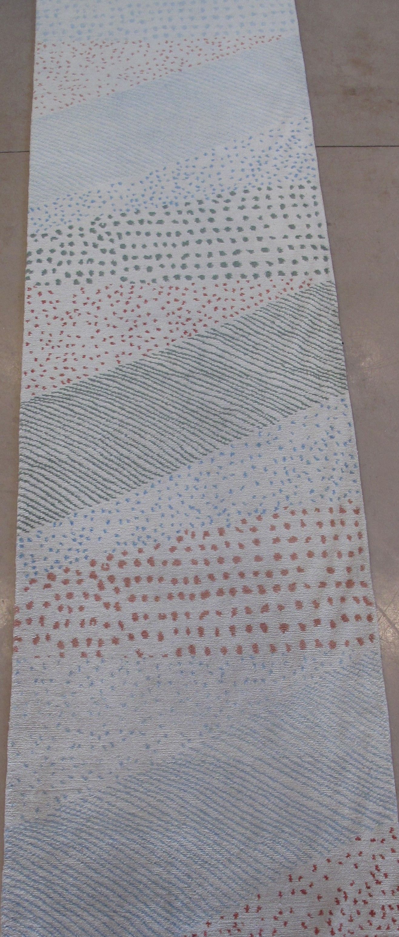 Long, narrow rug with light blue, gray, and brown stripes, and a dotted pattern.