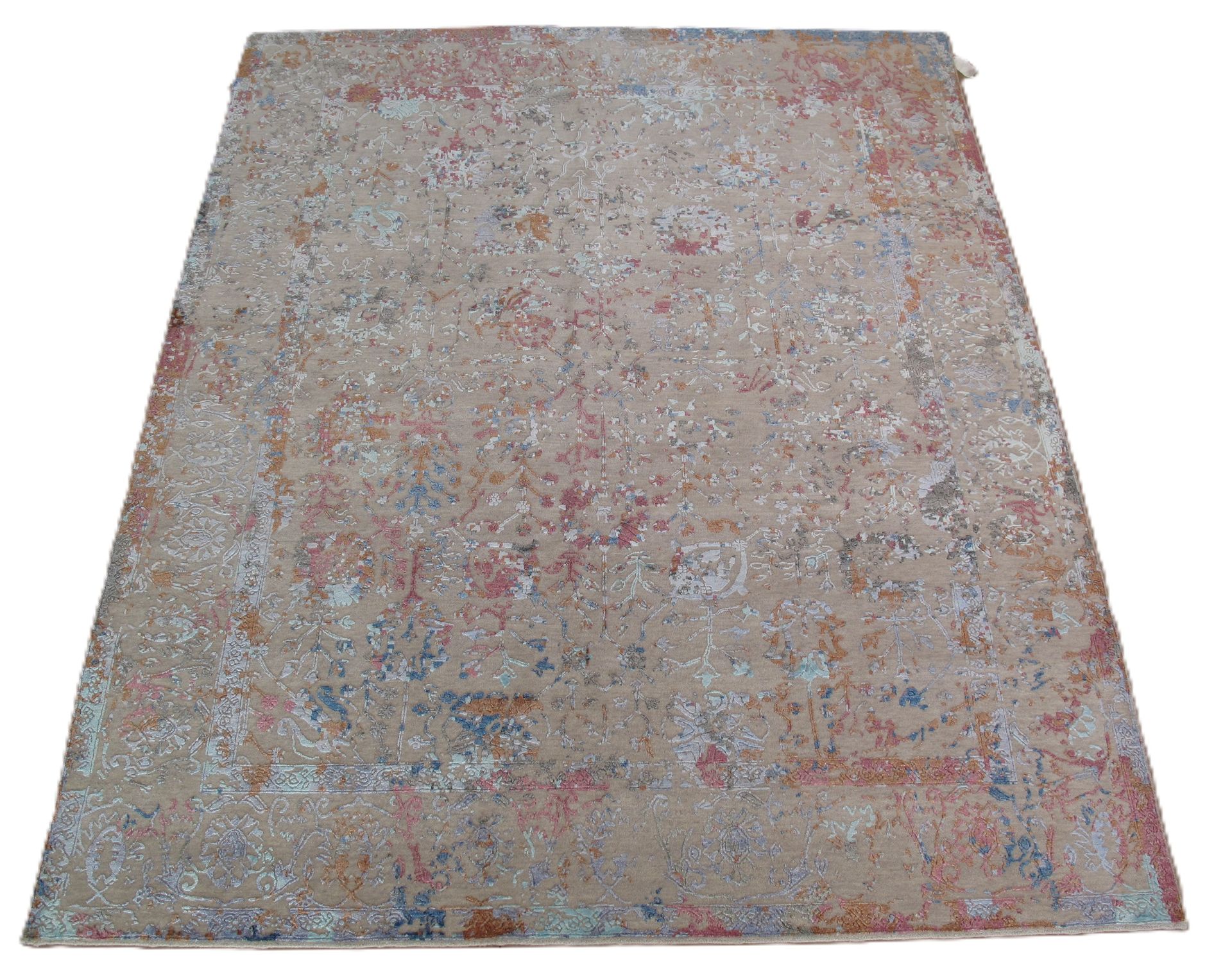 A rectangular area rug with a faded, distressed vintage pattern in shades of beige, muted orange, and soft blue.
