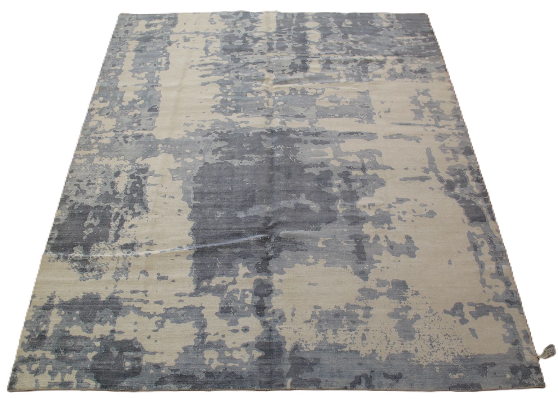An abstract area rug featuring a distressed, textured pattern in shades of gray and beige.