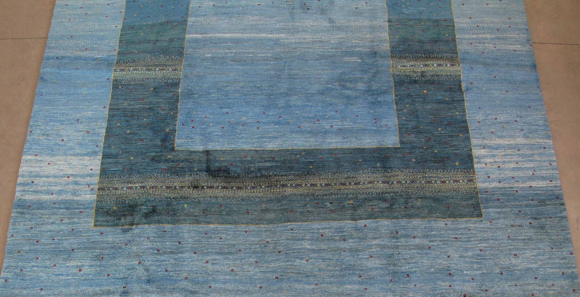 Blue and gray rectangular rug with a darker border and lighter center.