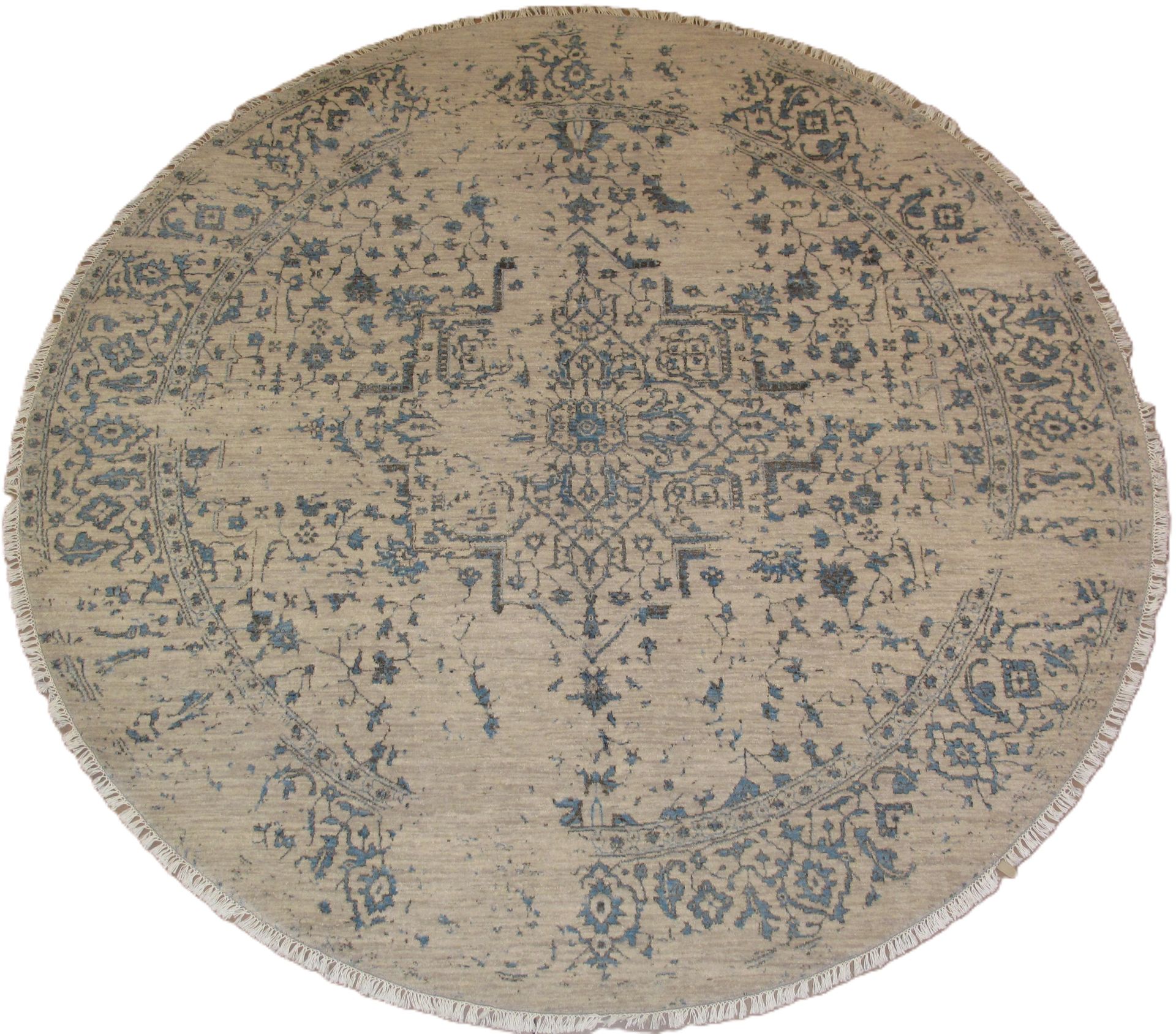 Round beige rug with faded blue floral pattern and fringed edge.