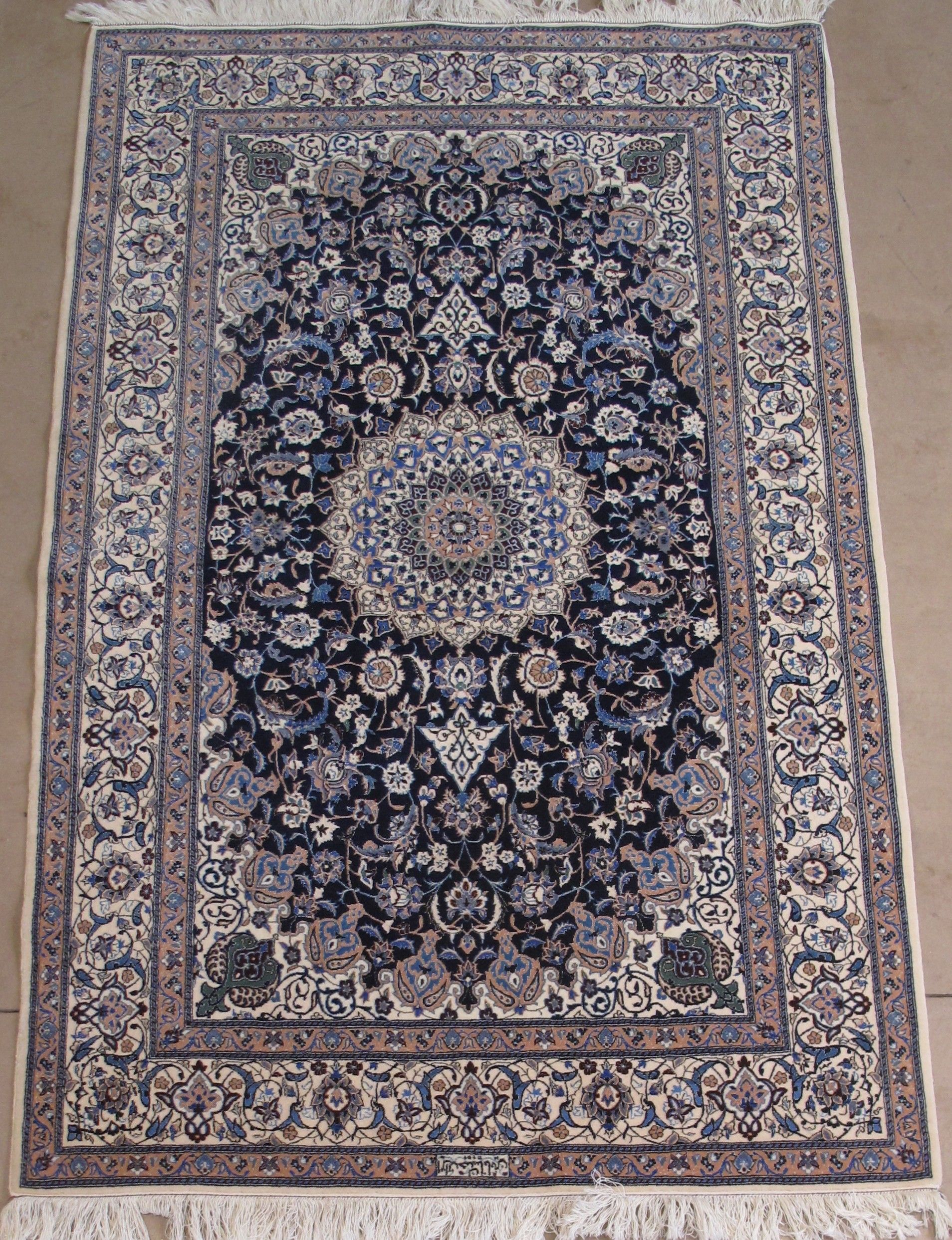 An ornate, rectangular Persian rug with a central medallion in blue and beige, surrounded by intricate floral patterns.