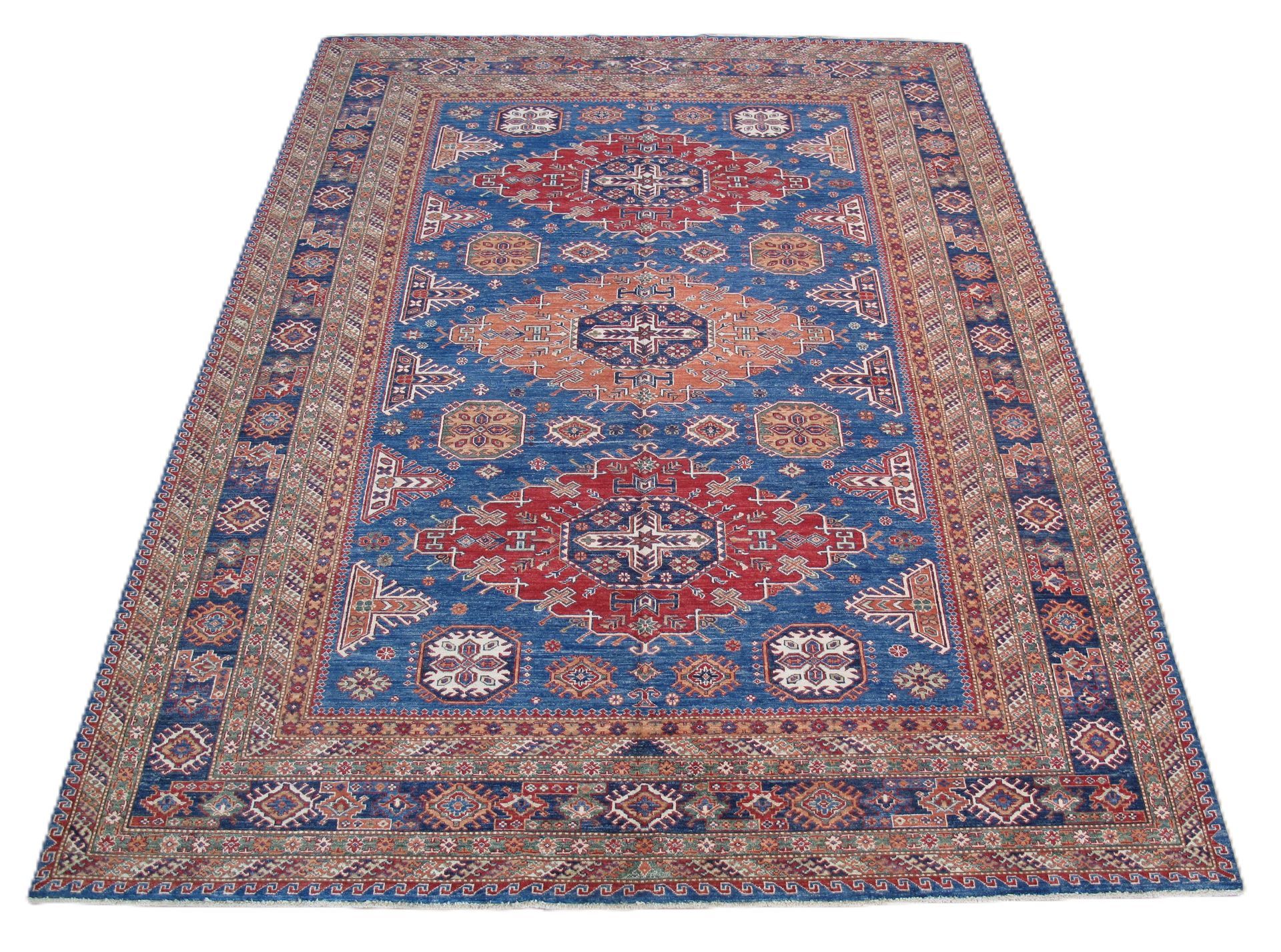 A rectangular rug with a blue field featuring red and tan geometric medallions and an ornate, patterned border.