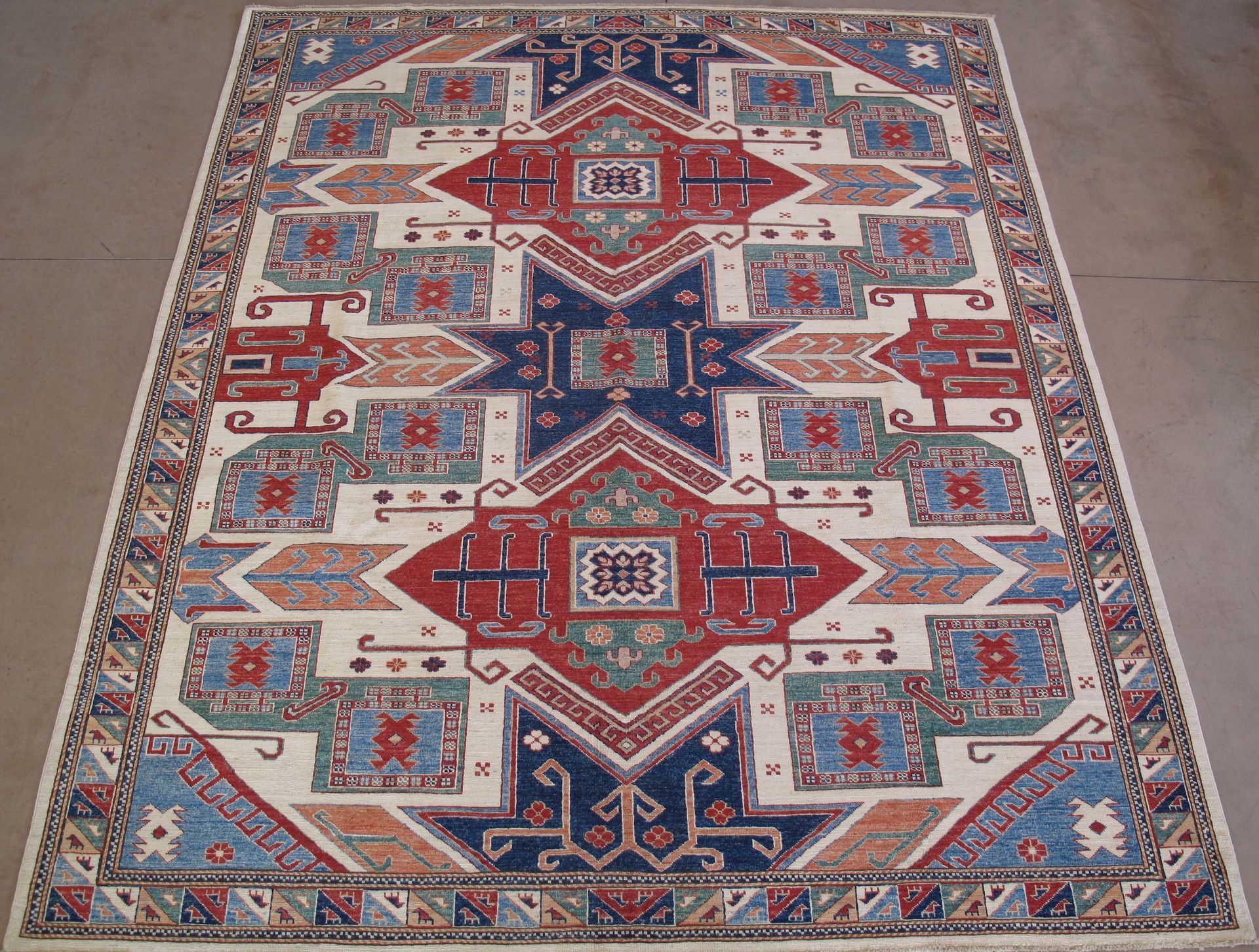 Cream-colored rug with geometric pattern in red, blue, and orange; visible perspective.