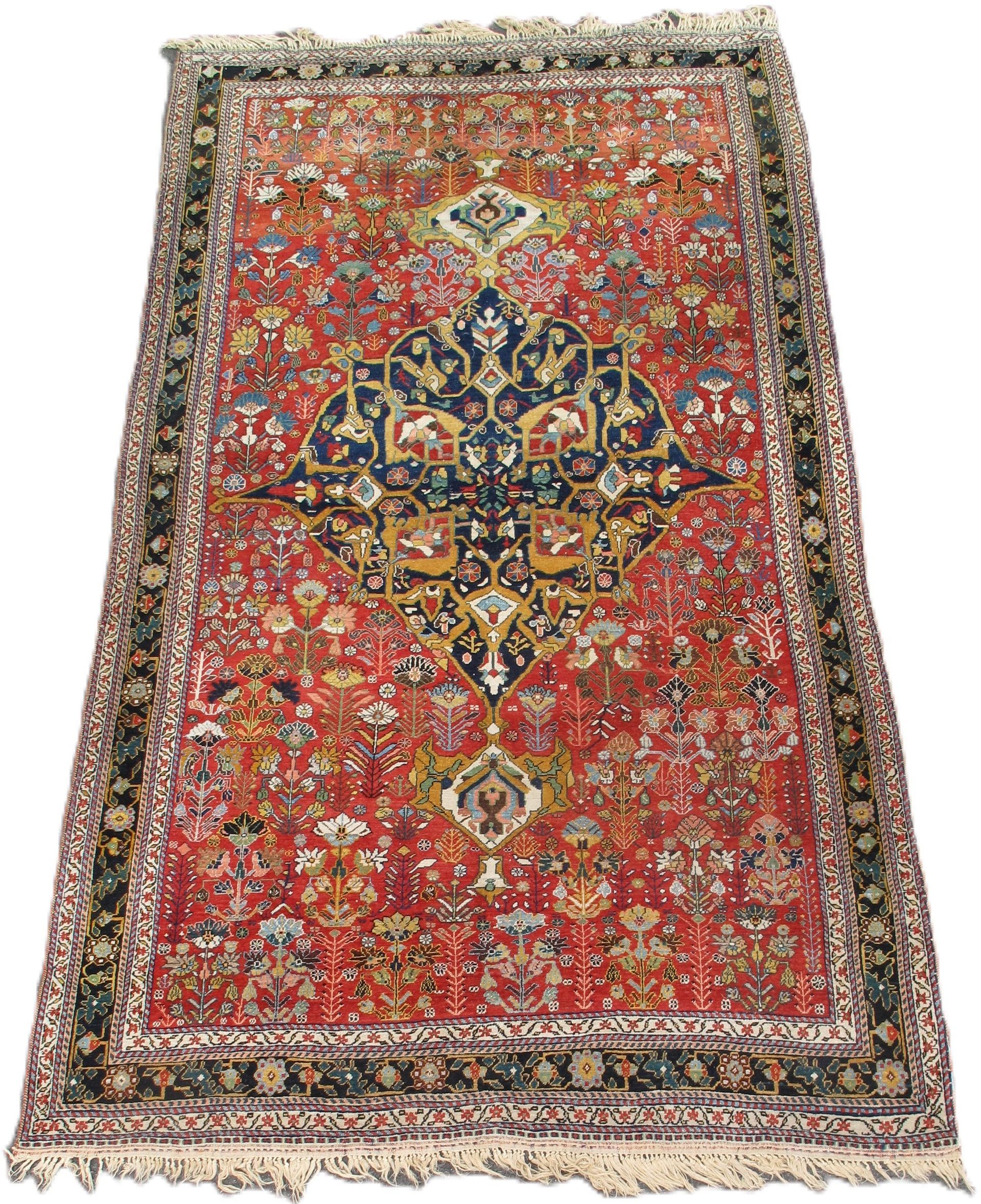 Red and navy Persian rug with floral motifs and border, ivory fringe.
