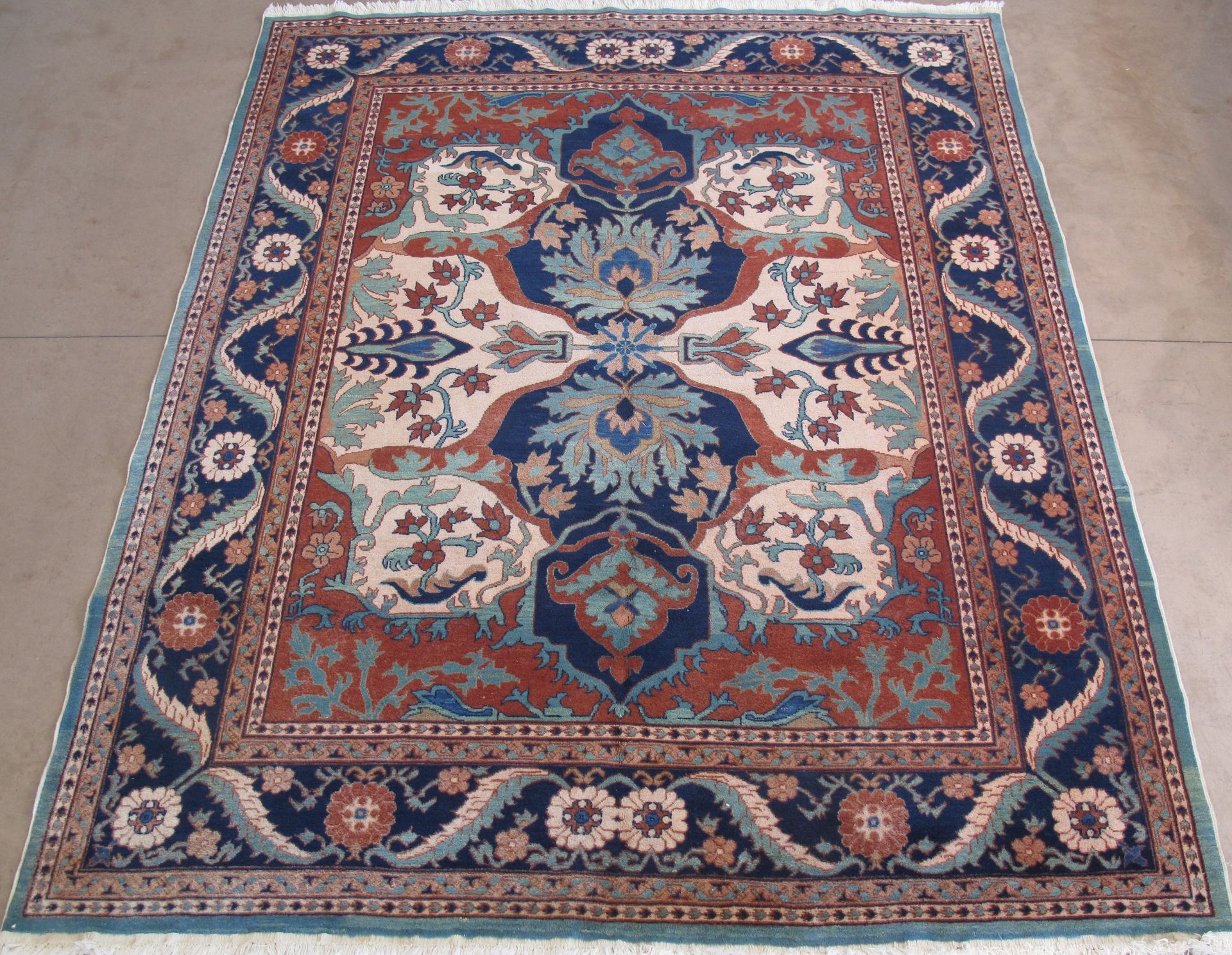 A rectangular rug with a blue and terracotta floral pattern and a fringed edge.