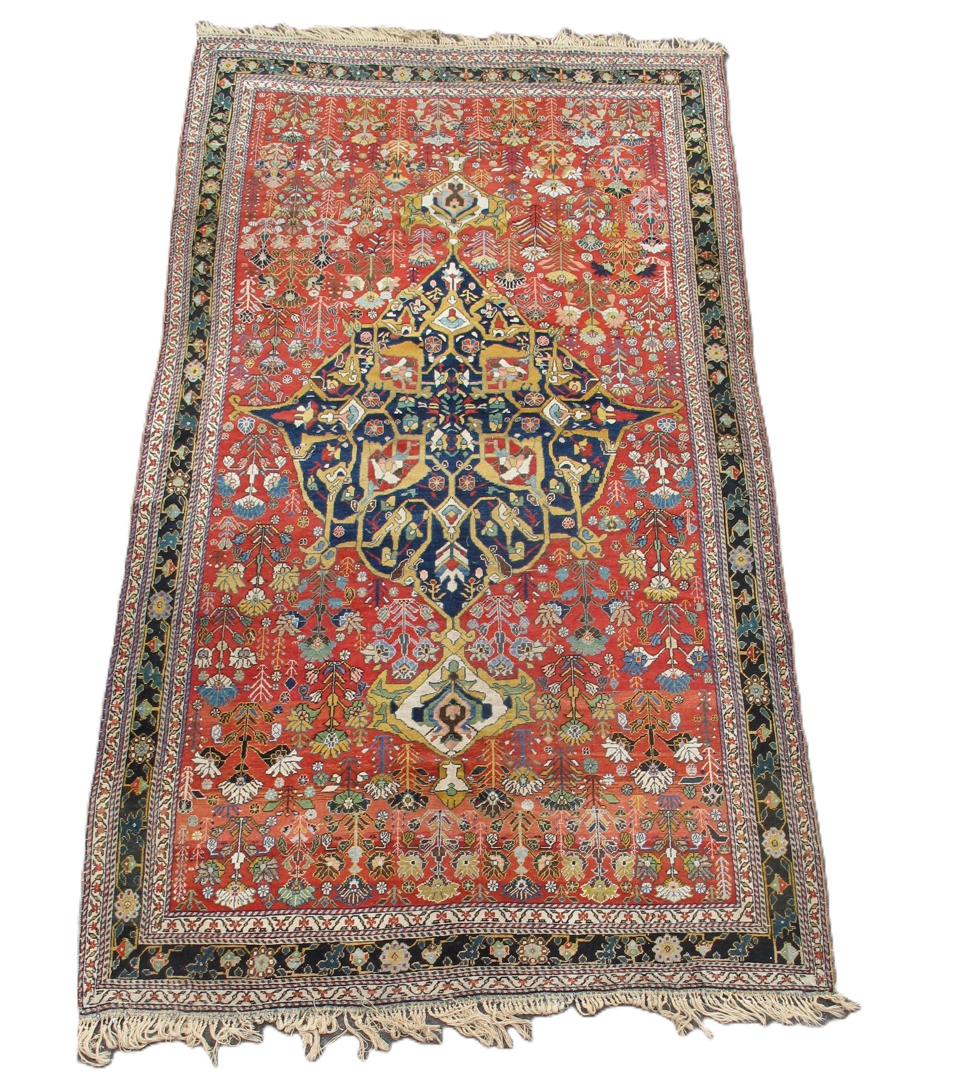 Red and navy Persian rug with floral motifs and border, ivory fringe.
