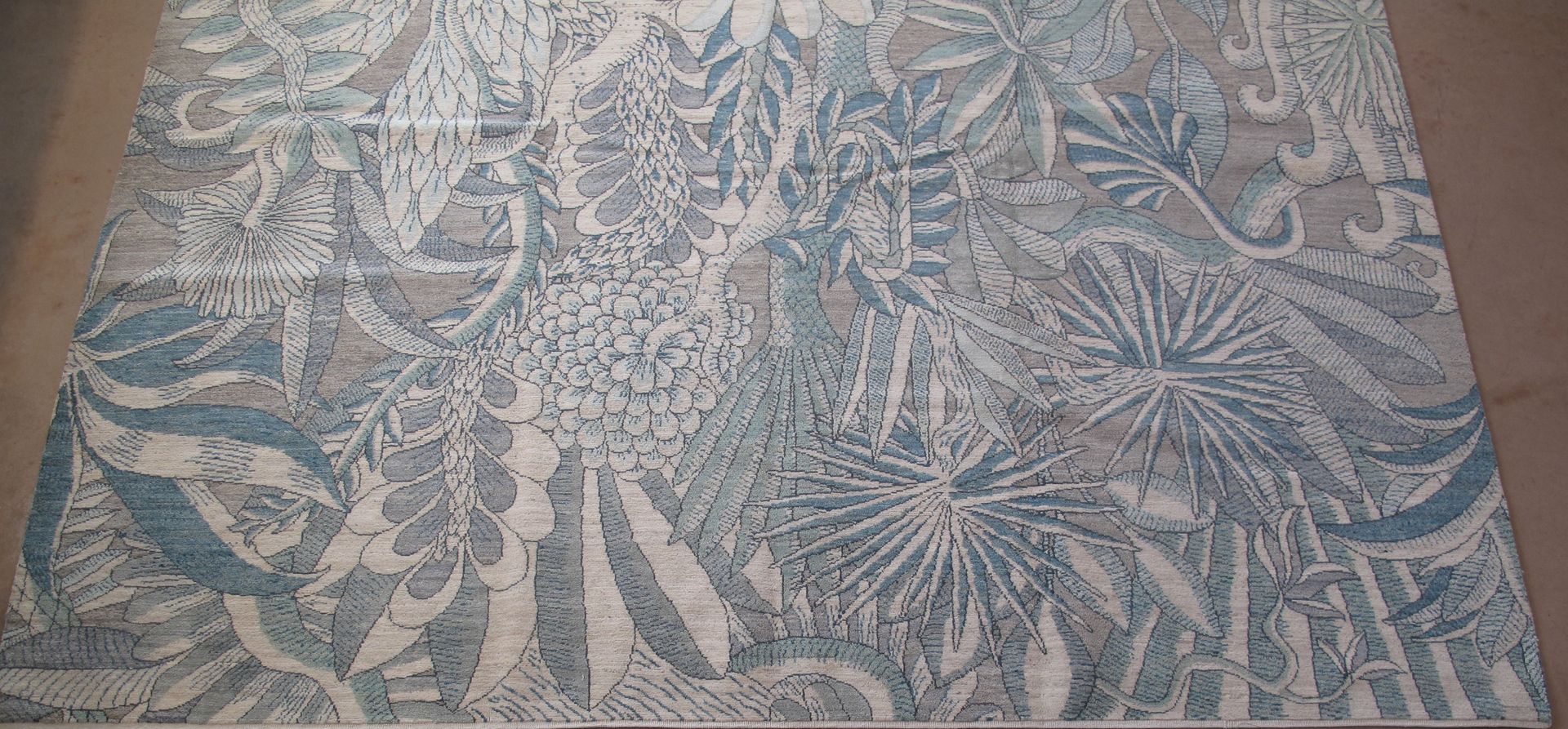 Large rug with blue and beige botanical pattern.