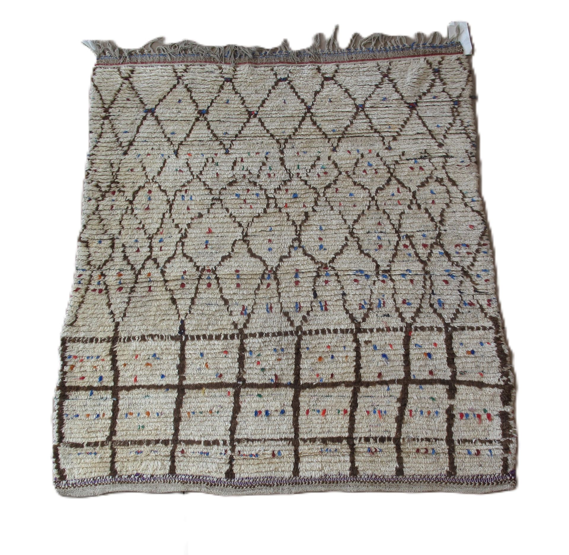 Beige rug with brown diamond and grid pattern, scattered red and blue dots.