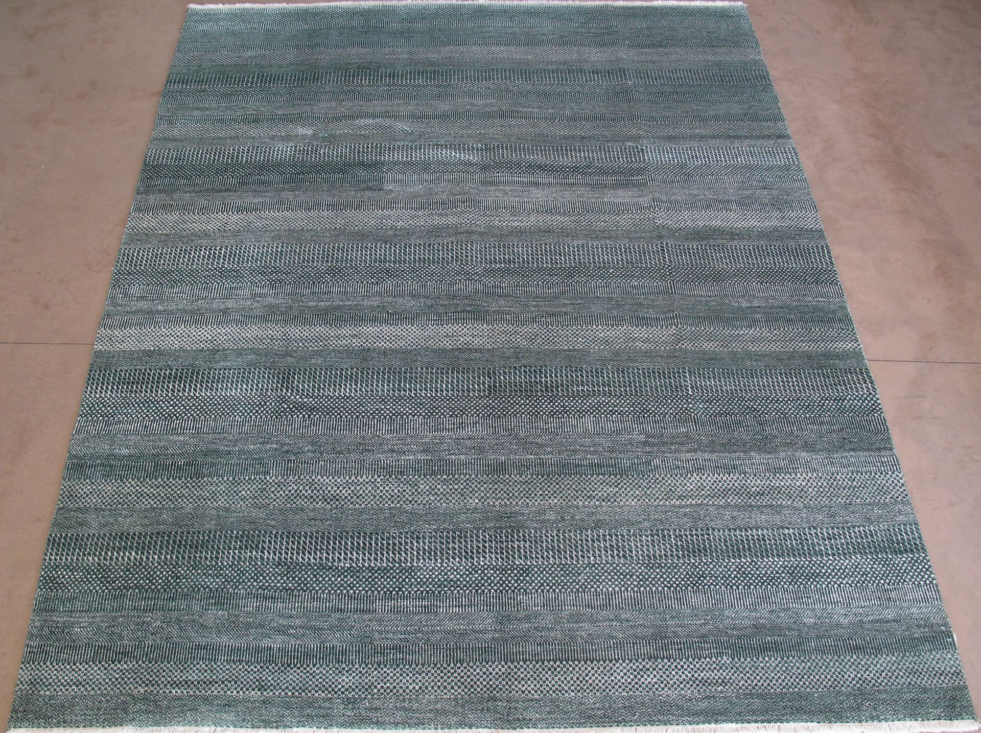 A dark gray area rug with a textured, wavy, or ribbed pattern, displayed from an angled perspective.