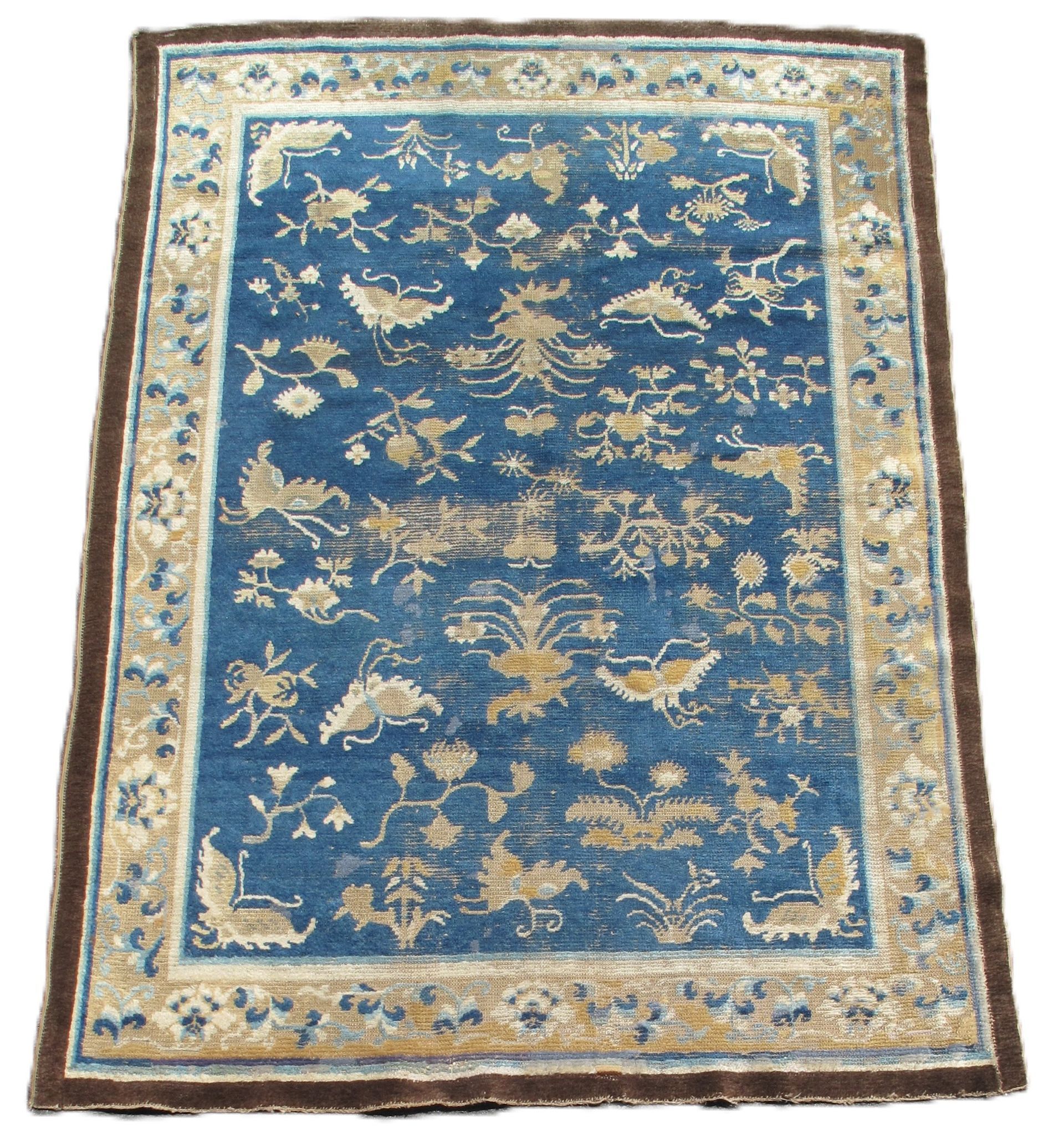 Blue floral patterned rug with beige border and brown edges