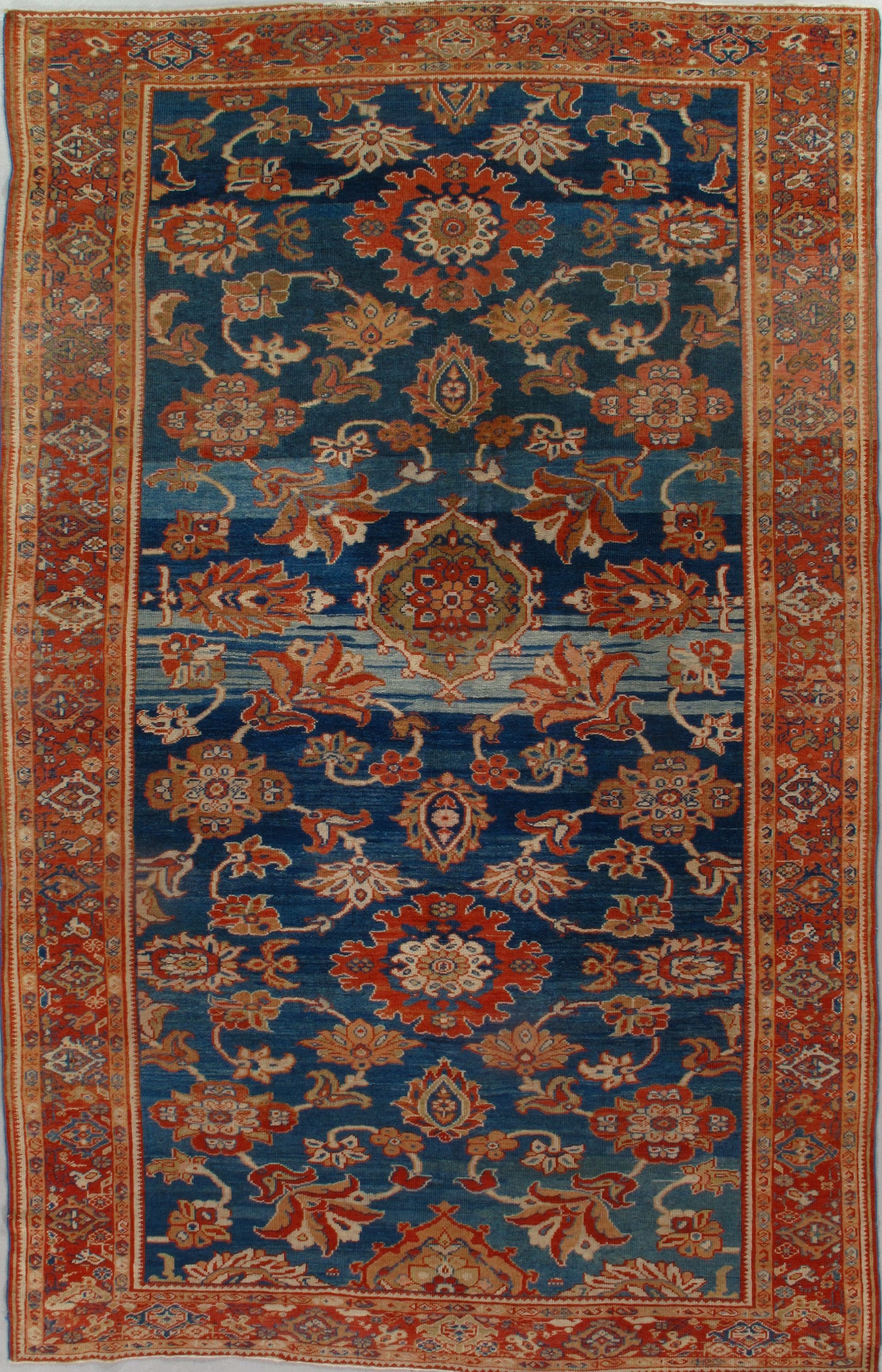 Antique Persian rug with blue field, floral motifs, and red border.