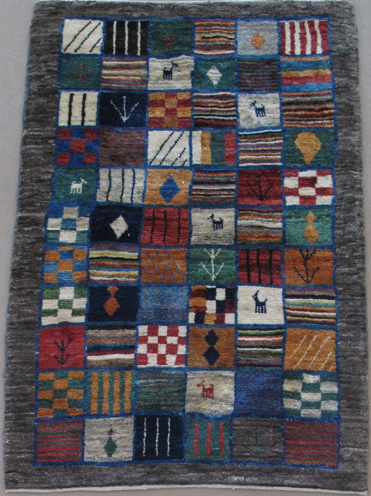 A rectangular rug with a patchwork grid of squares featuring diverse abstract symbols, patterns, and colorful designs.