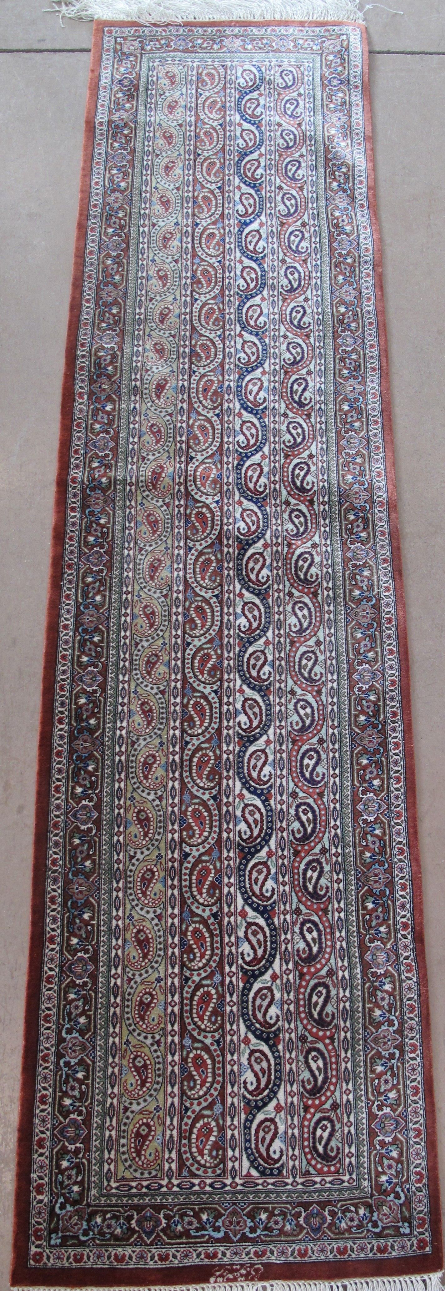 Long rectangular patterned rug in red, blue, and white with decorative border