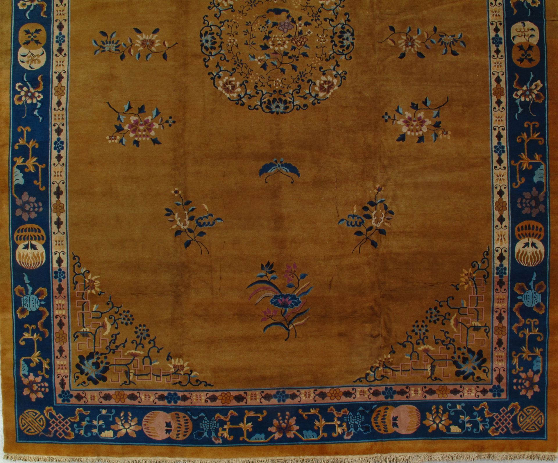 Close-up of a golden yellow oriental rug with blue floral border and center medallion design.