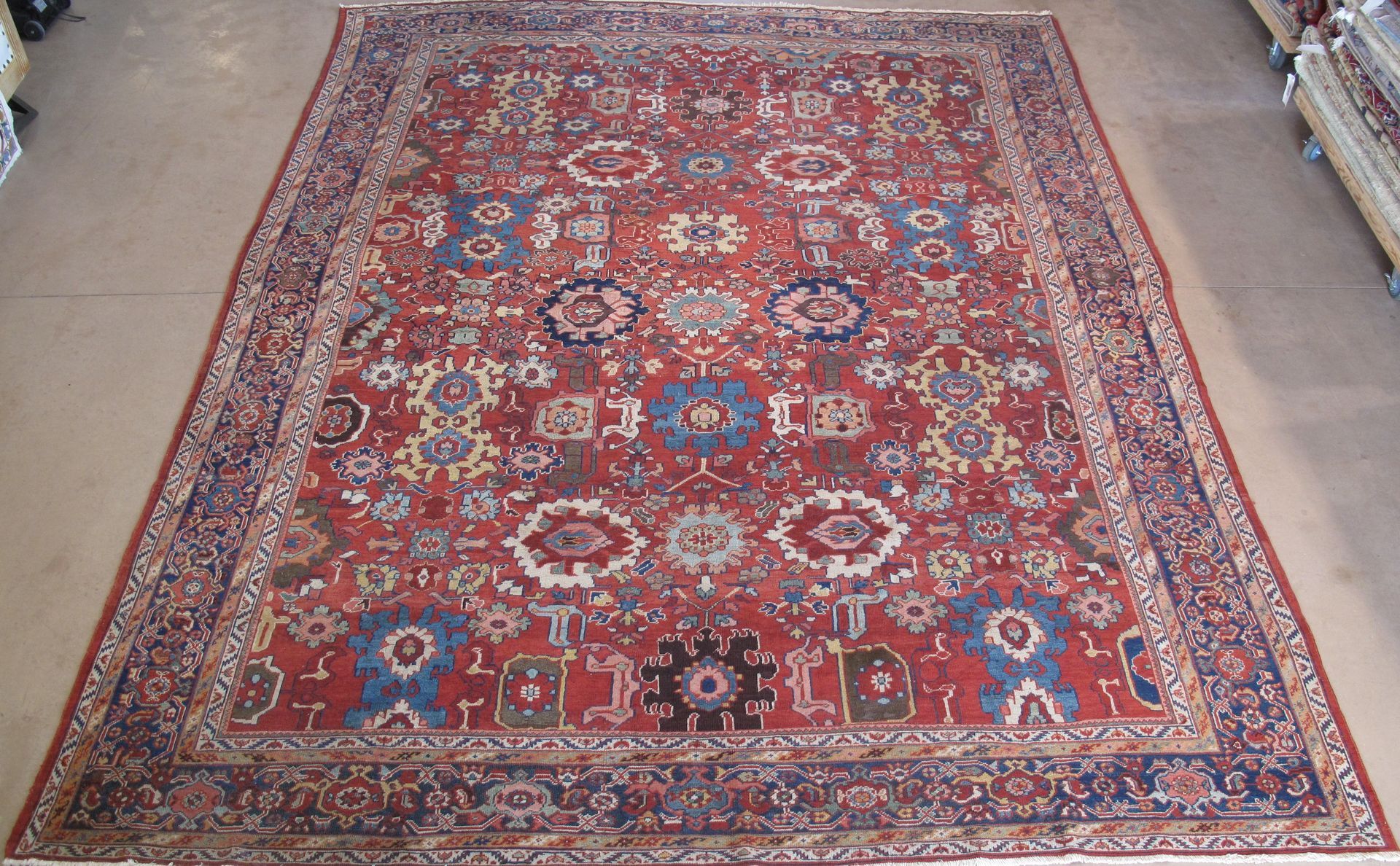 Red patterned Oriental-style rug with blue and cream floral motifs on a white background