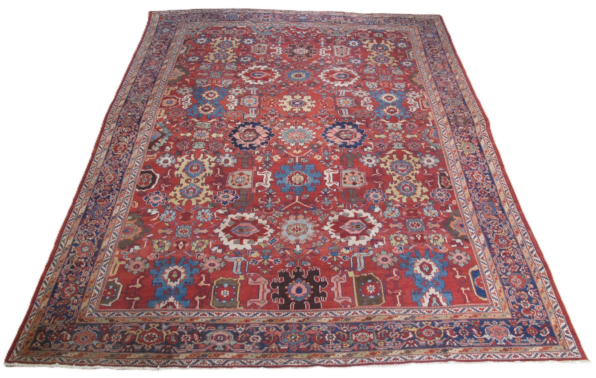 Red patterned Oriental-style rug with blue and cream floral motifs on a white background