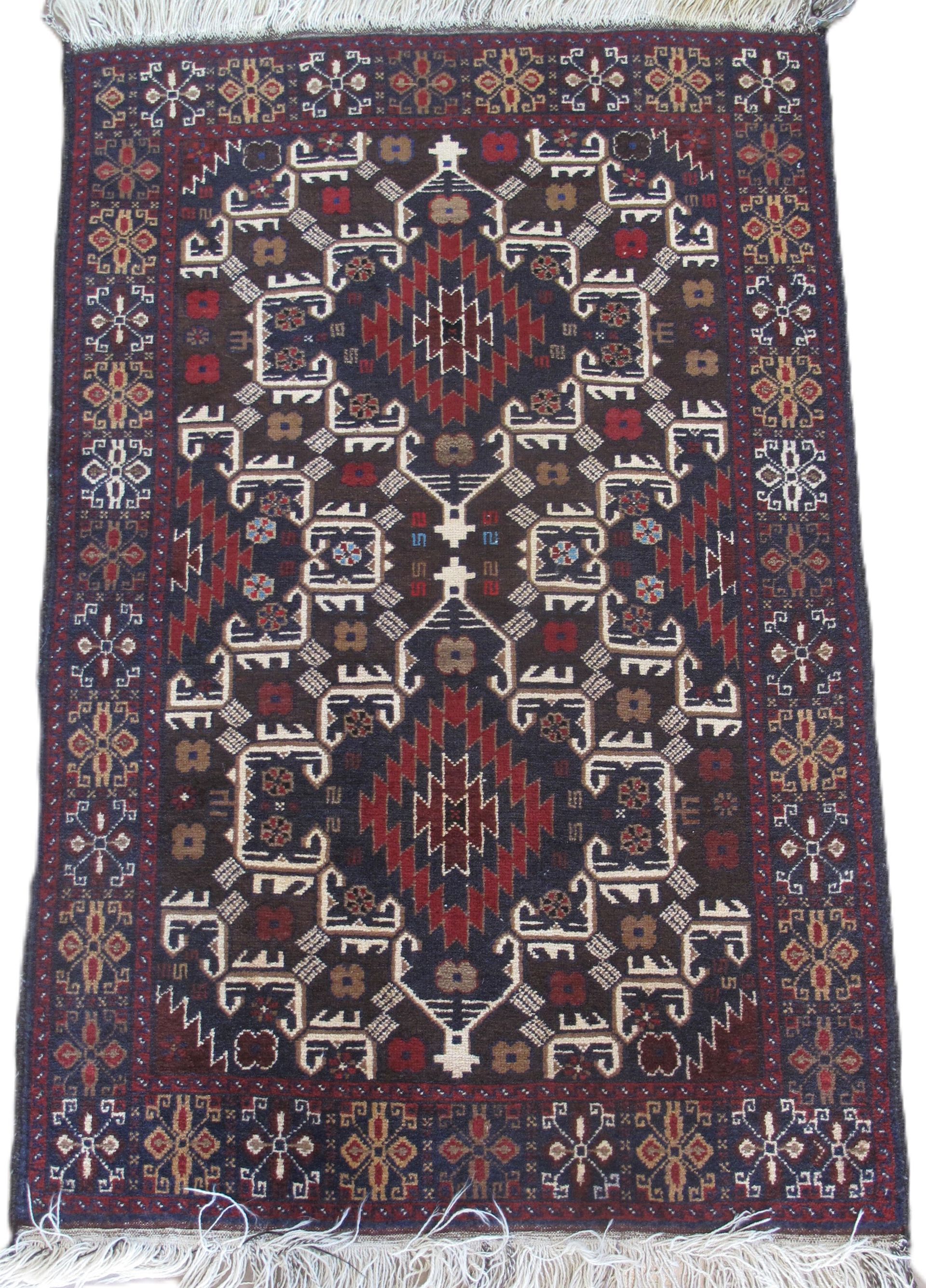 An ornate, rectangular rug with a dark red and cream geometric design and fringe.