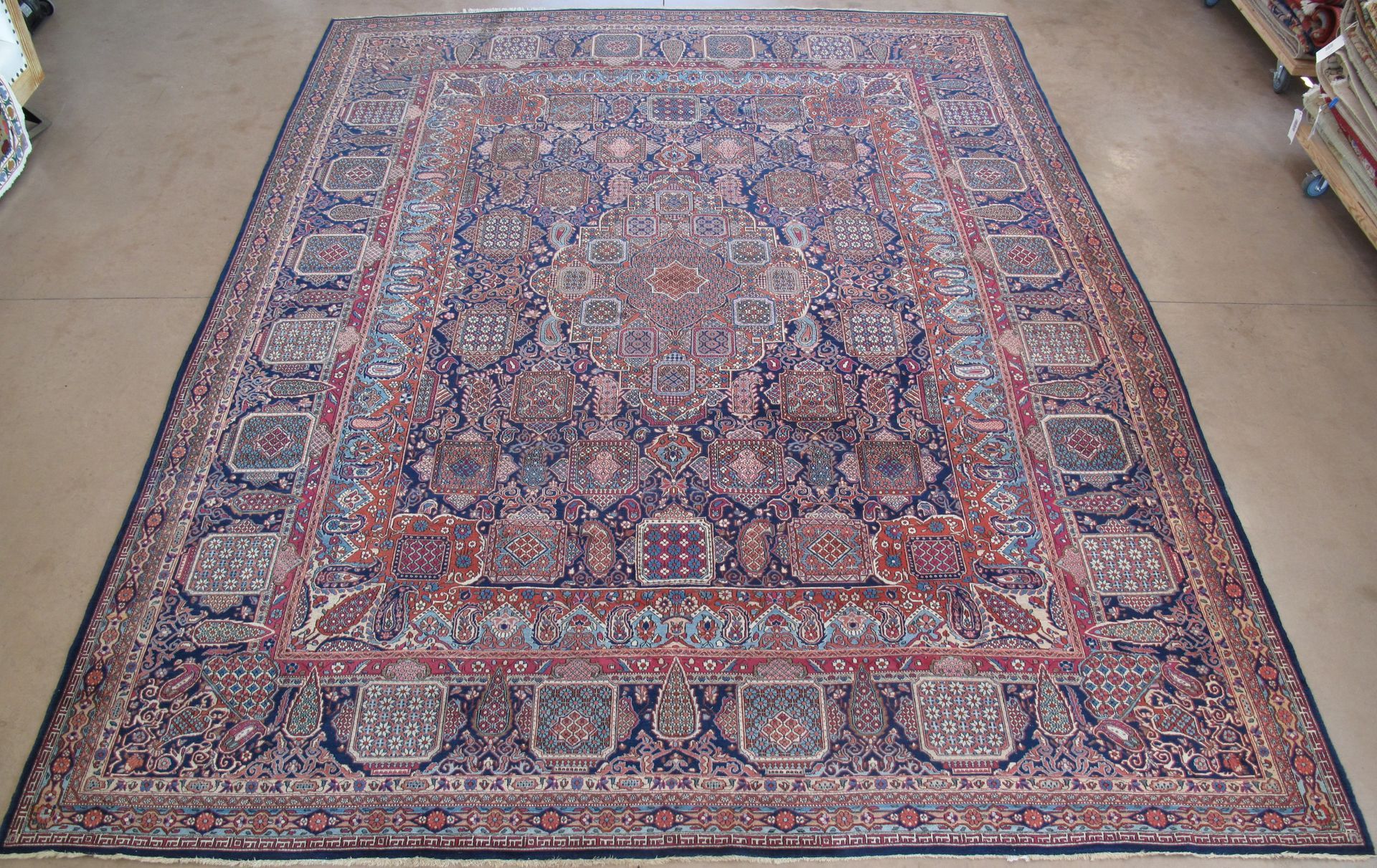 Large antique Persian rug with intricate floral and geometric patterns, blue and red hues.