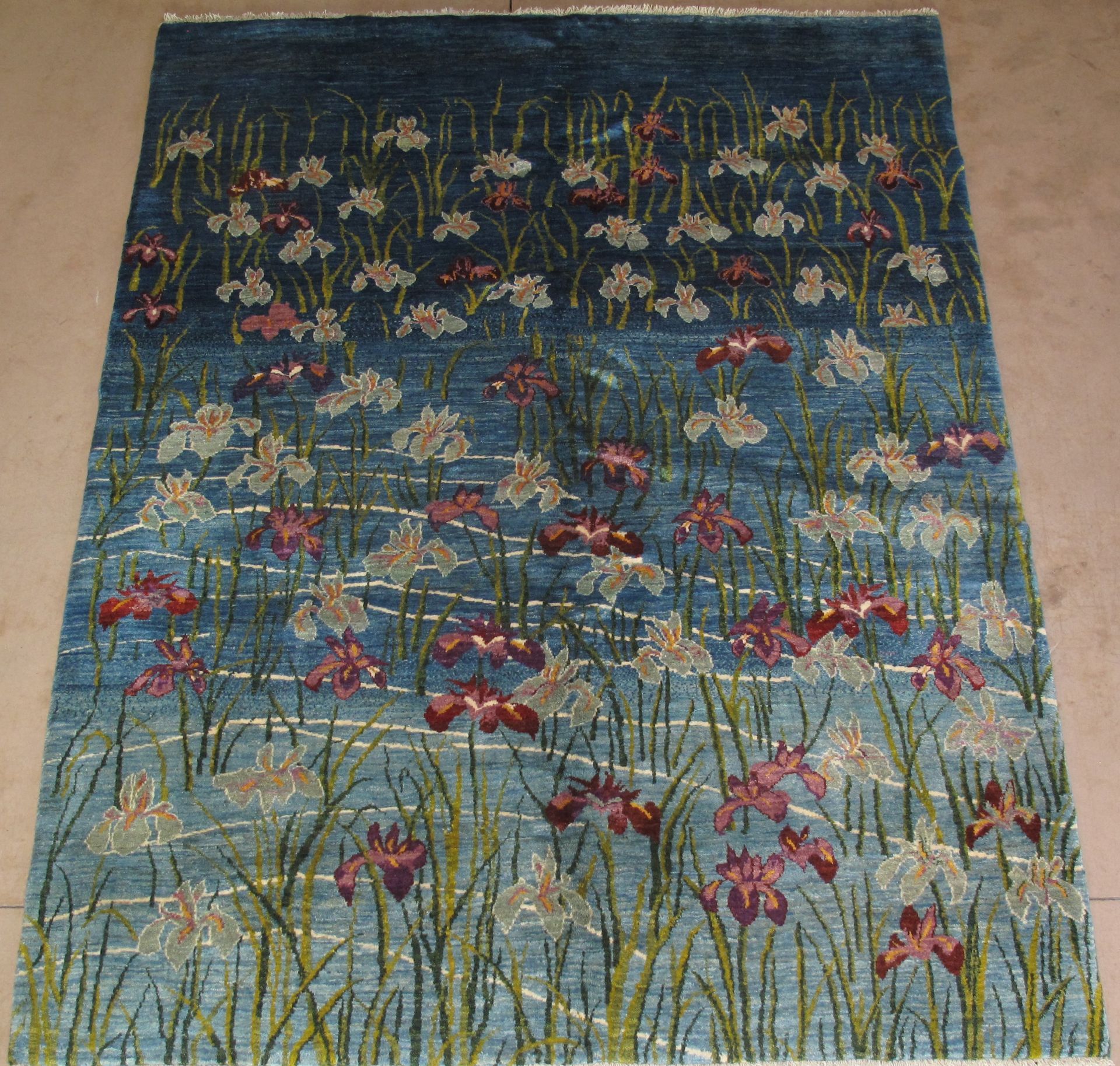 Floral rug with blue background, red and white flowers, and green stalks.