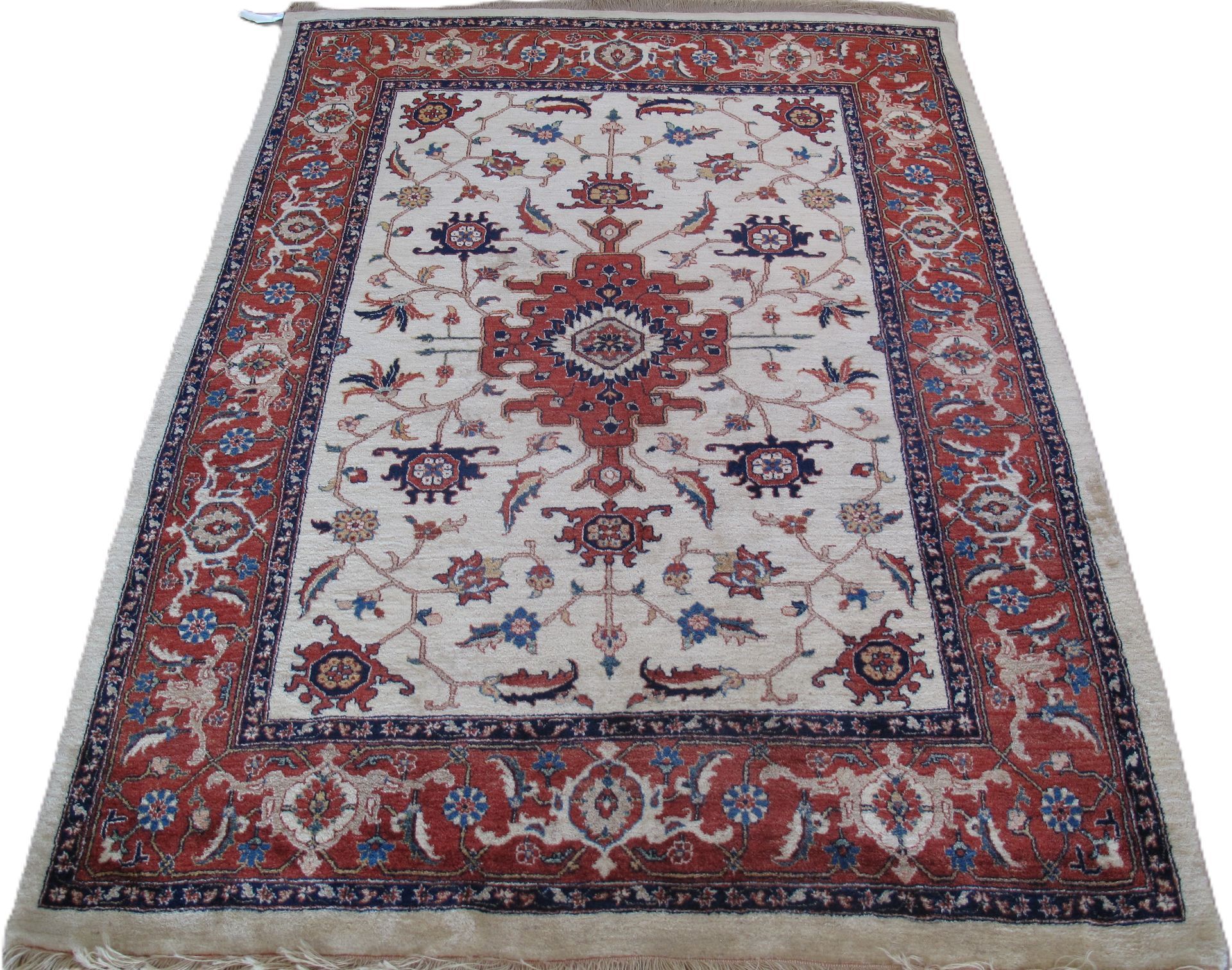 Oriental rug with a beige center, ornate red and blue border, and a red medallion.