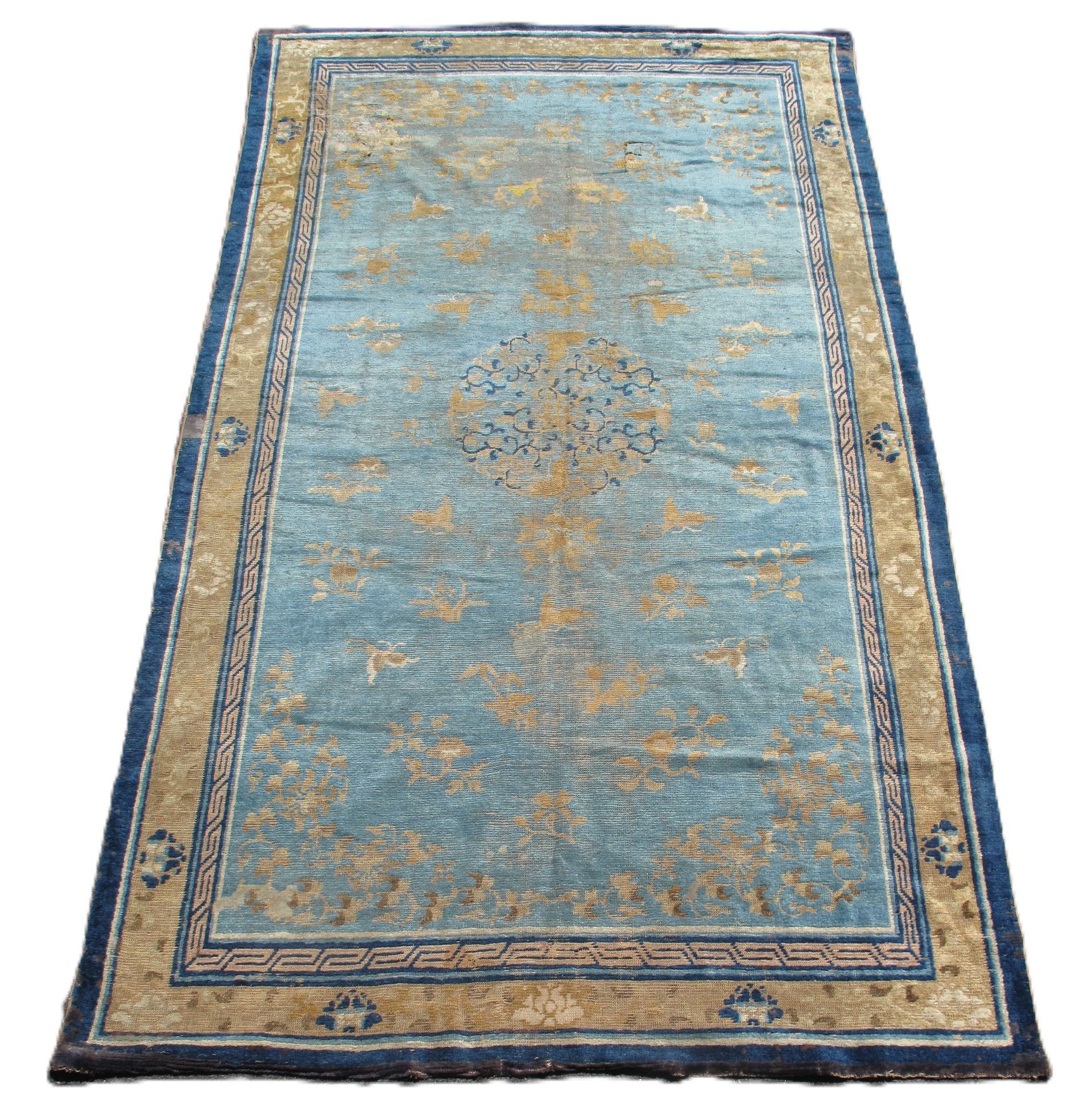 Blue vintage rug with beige border and faded floral pattern on a white background