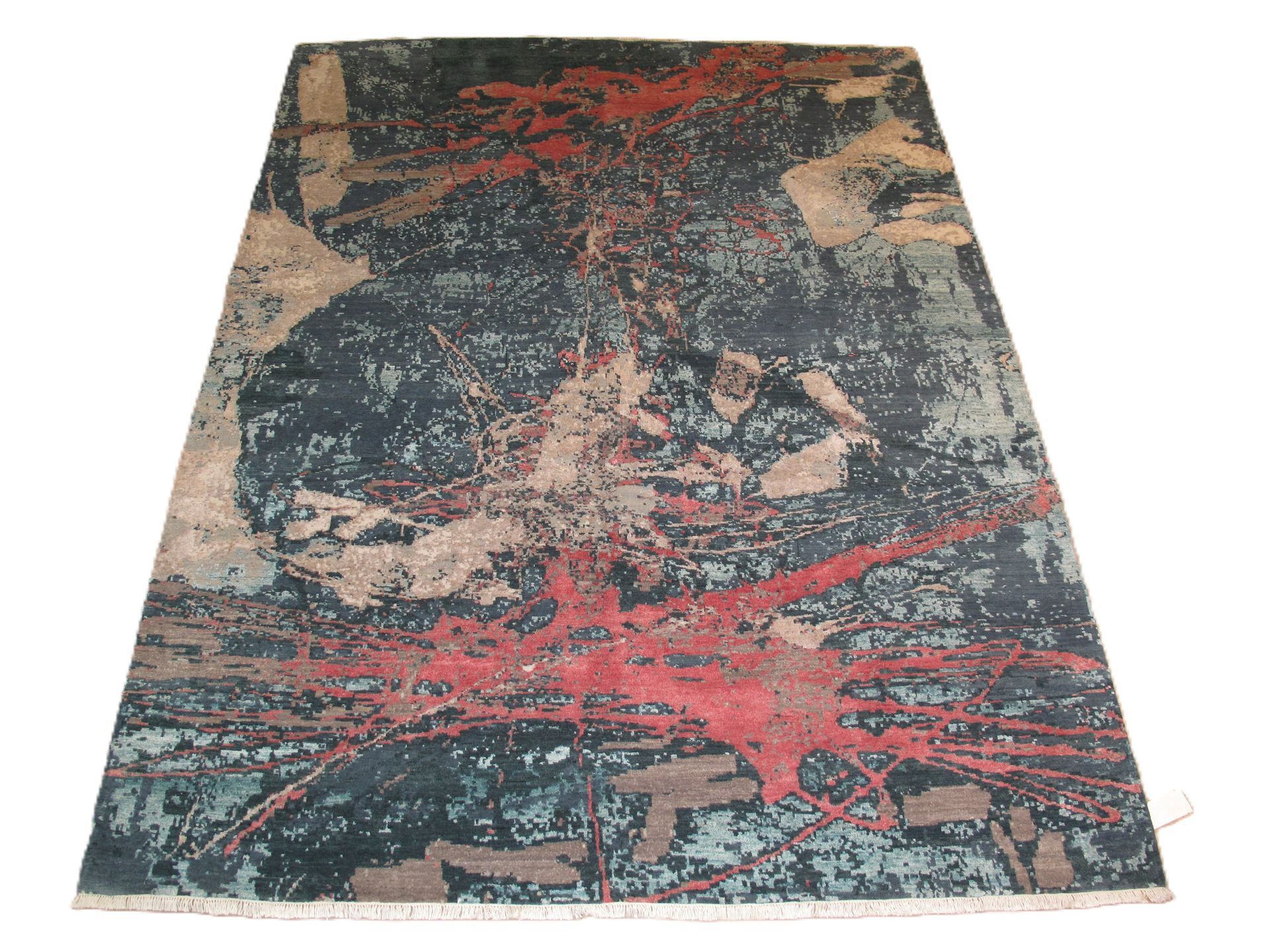 Abstract rug with red splatters on a dark blue and tan background.
