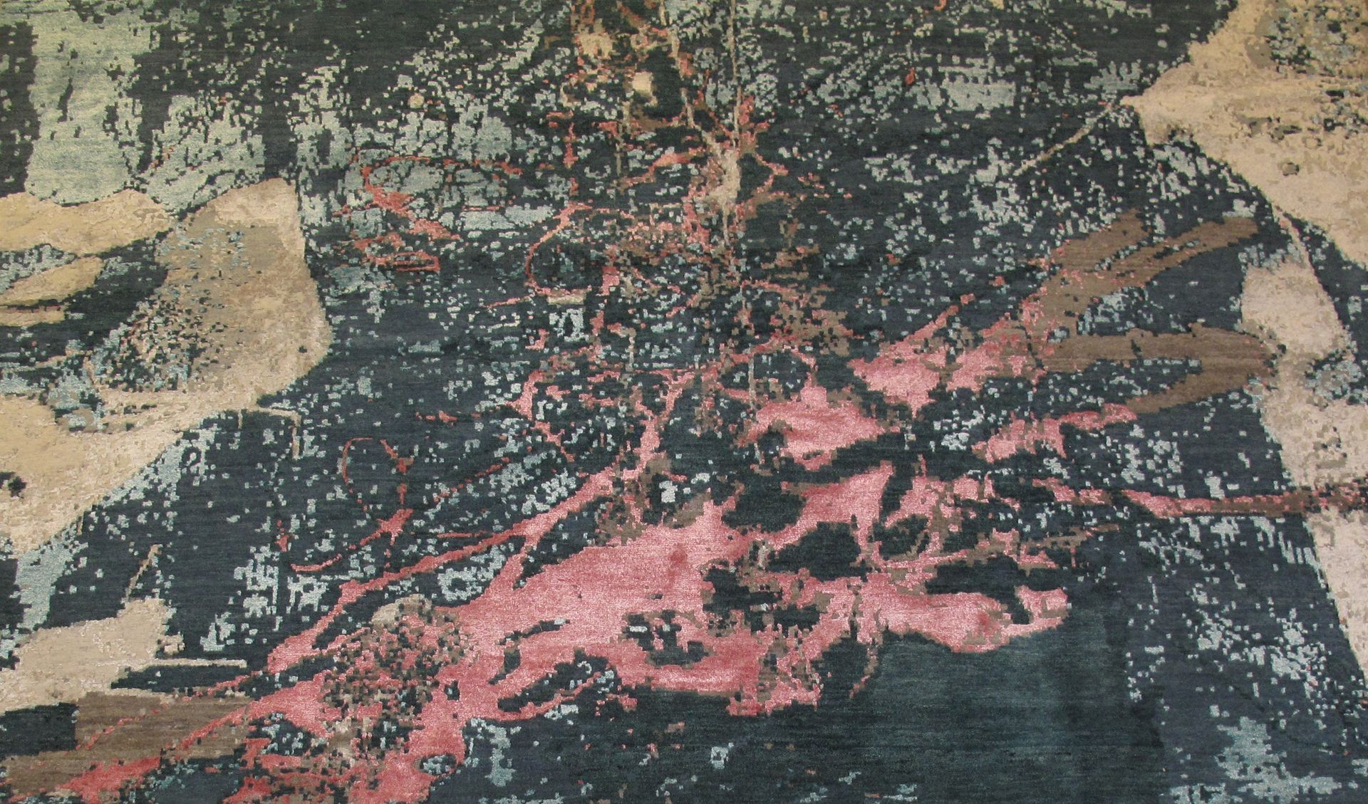 Abstract rug with red splatters on a dark blue and tan background.