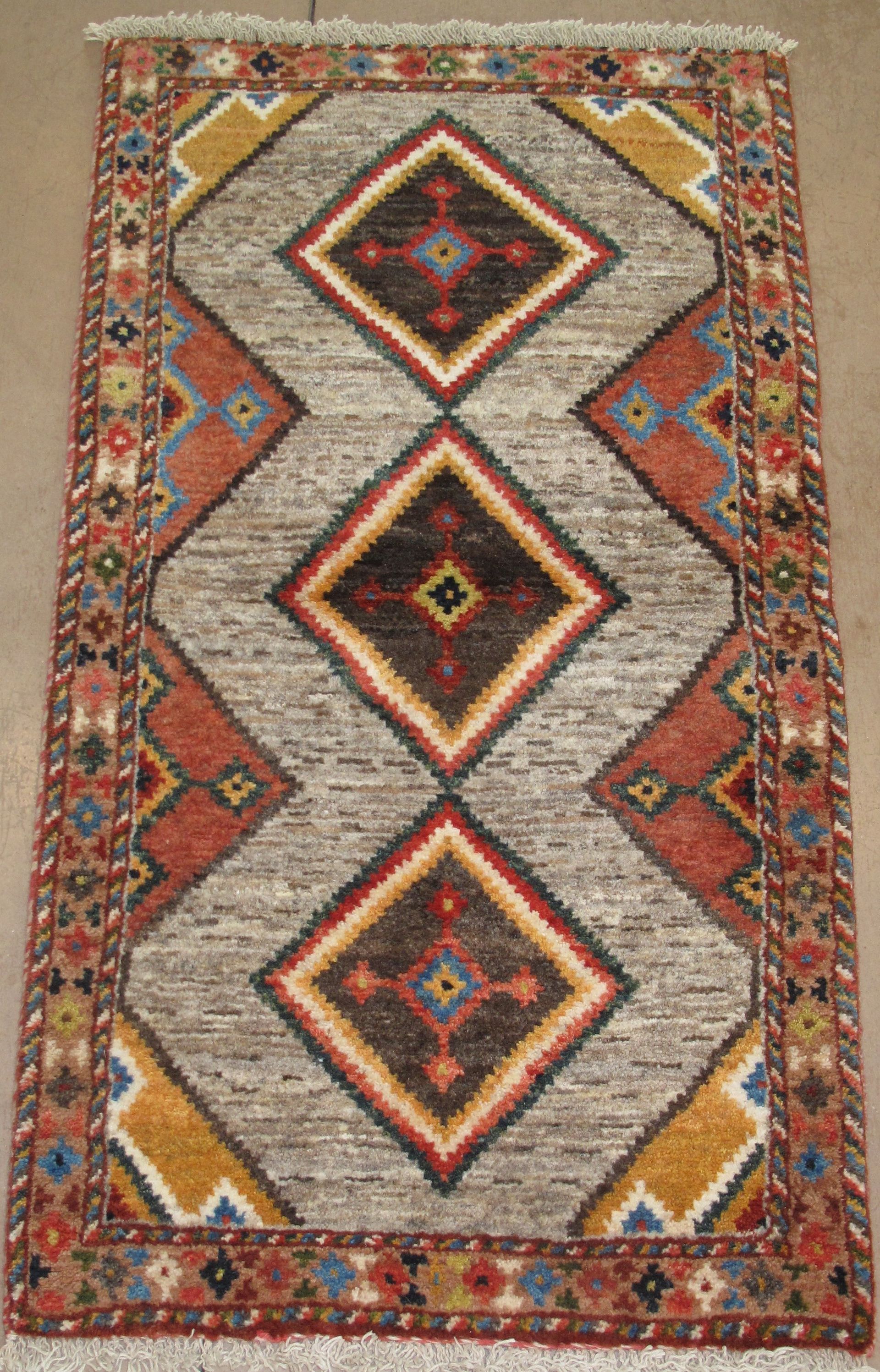 Colorful geometric woven rug with diamond patterns in red, orange, black, and cream