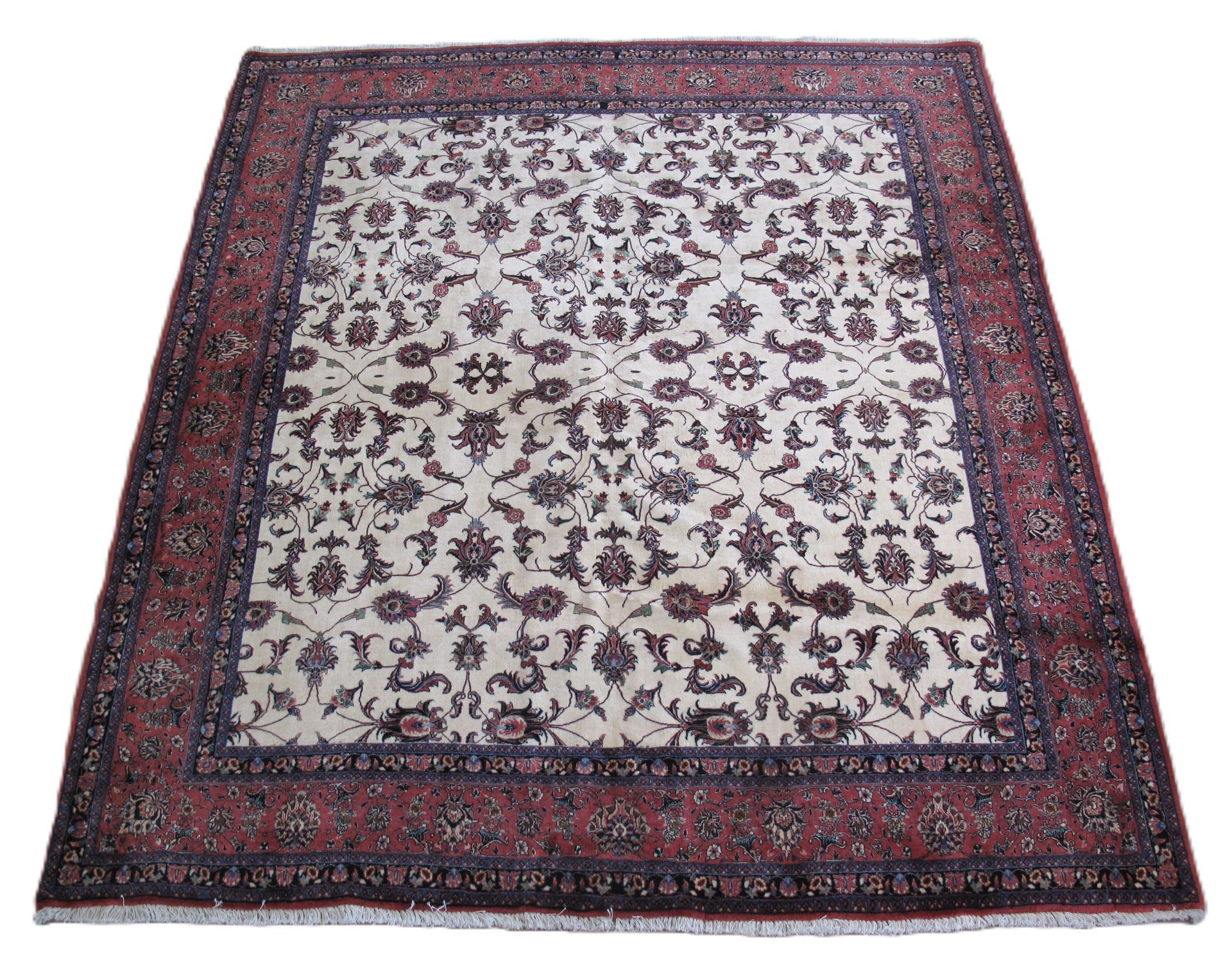 An ornate, rectangular area rug featuring a cream-colored field with floral patterns, bordered by deep red and navy tones.