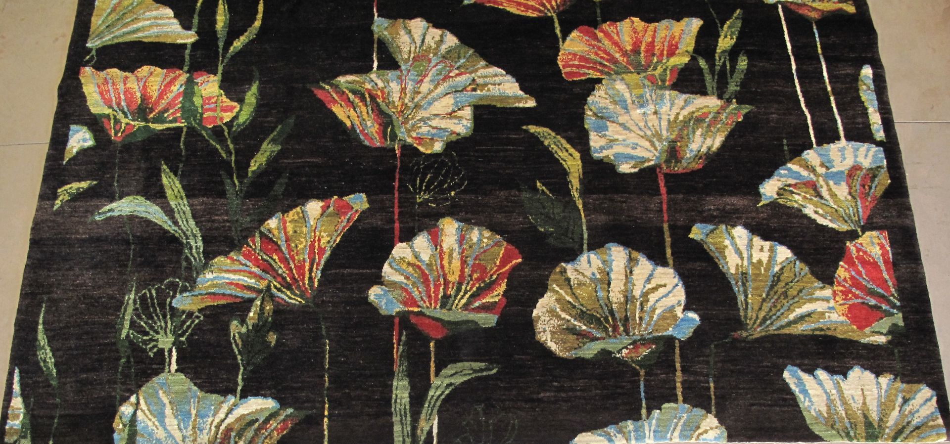 Floral patterned rug with orange, blue, and yellow flowers on a black background.