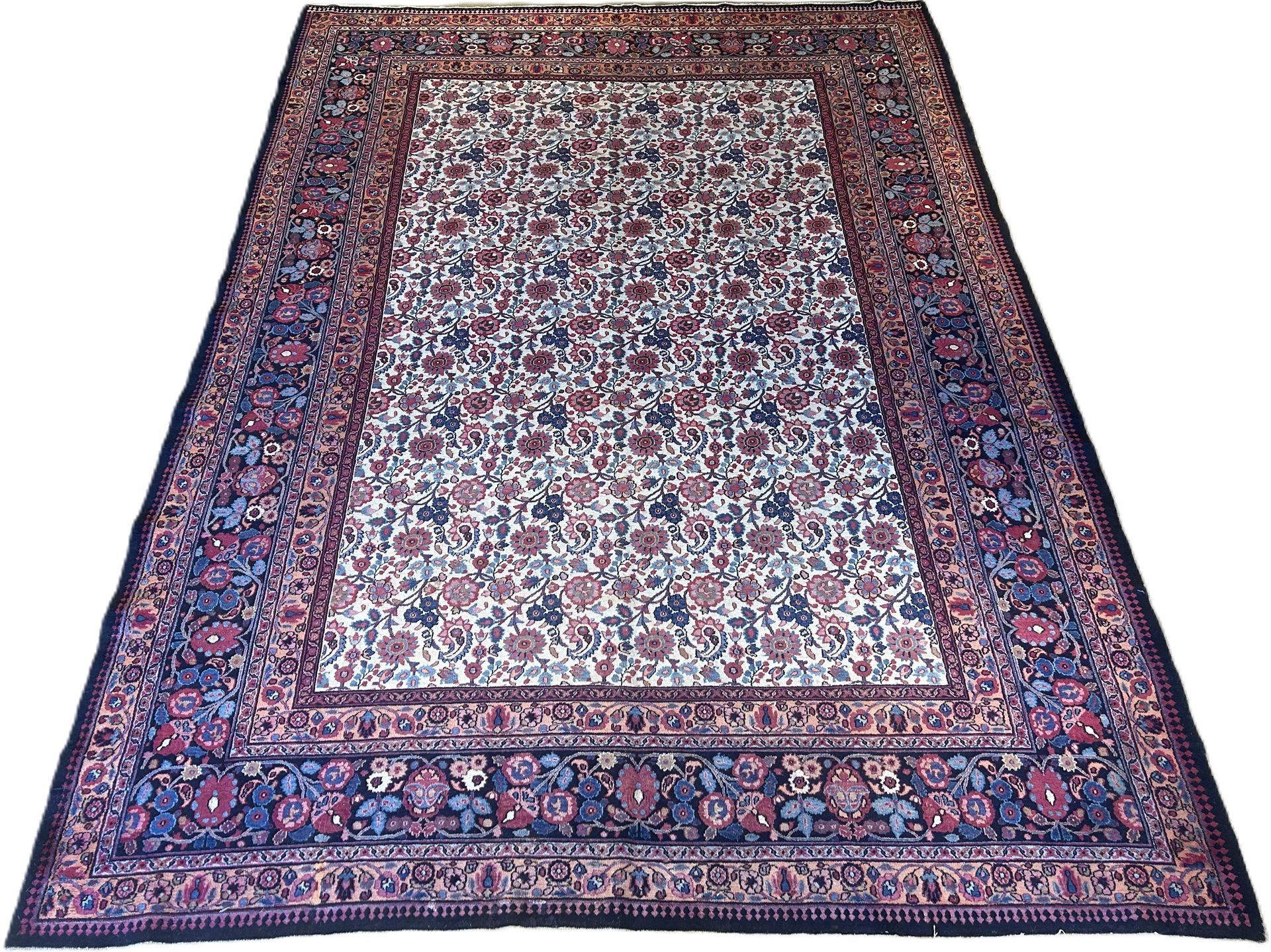 A rectangular rug with an off-white floral field surrounded by a wide, dark blue border filled with intricate motifs.