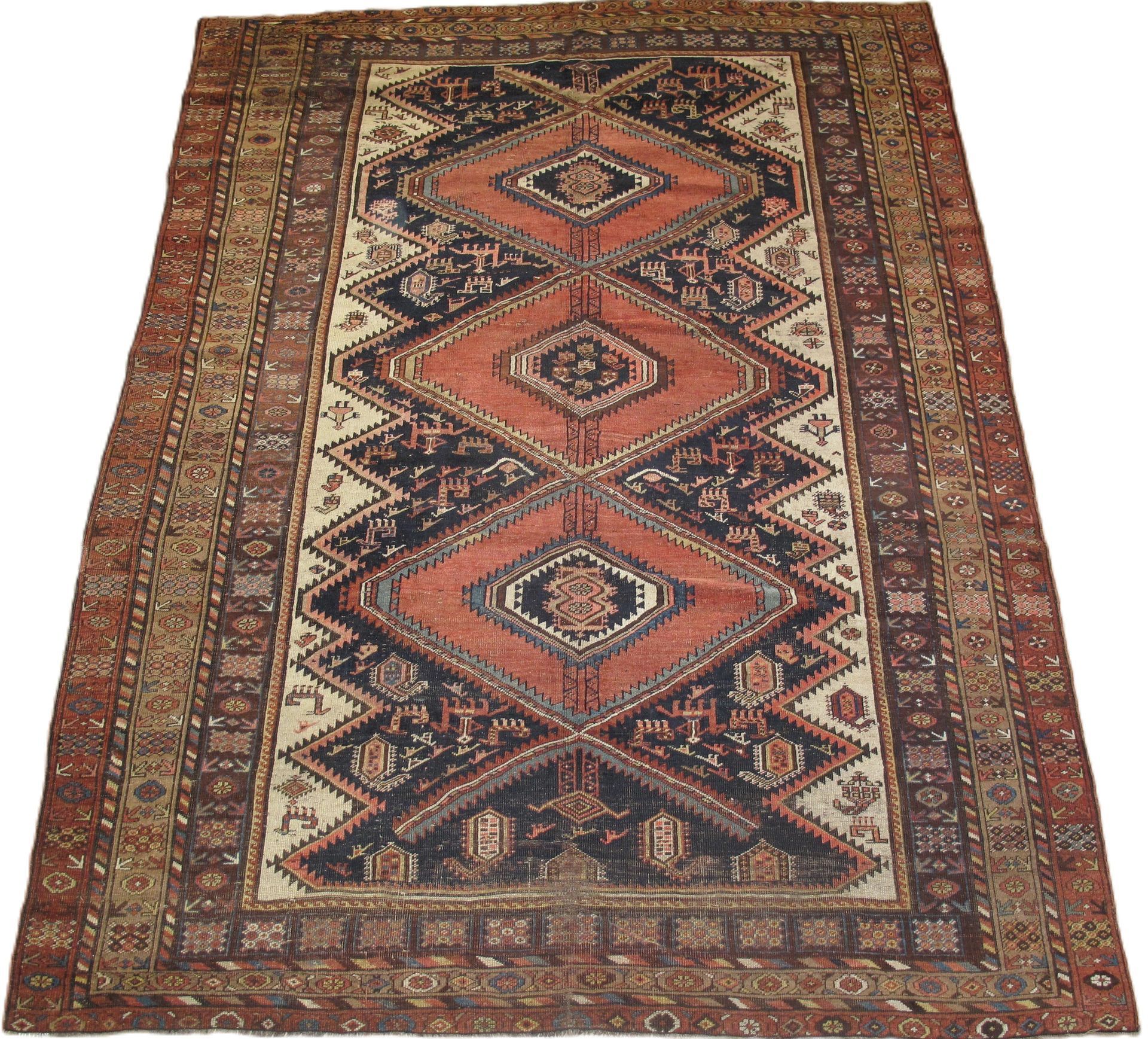 An antique rug with a central diamond pattern in red, black, and beige, with a patterned border.