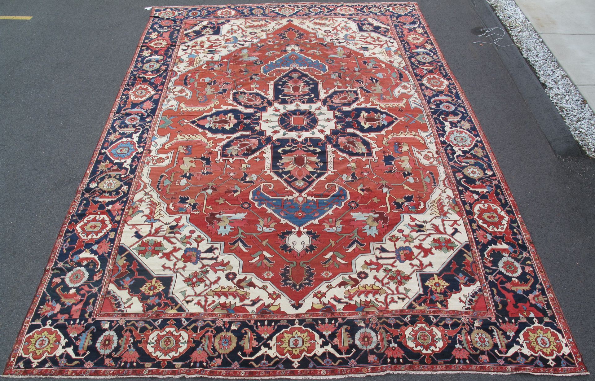 Patterned red and navy oriental area rug with ornate floral border, shown on a white background