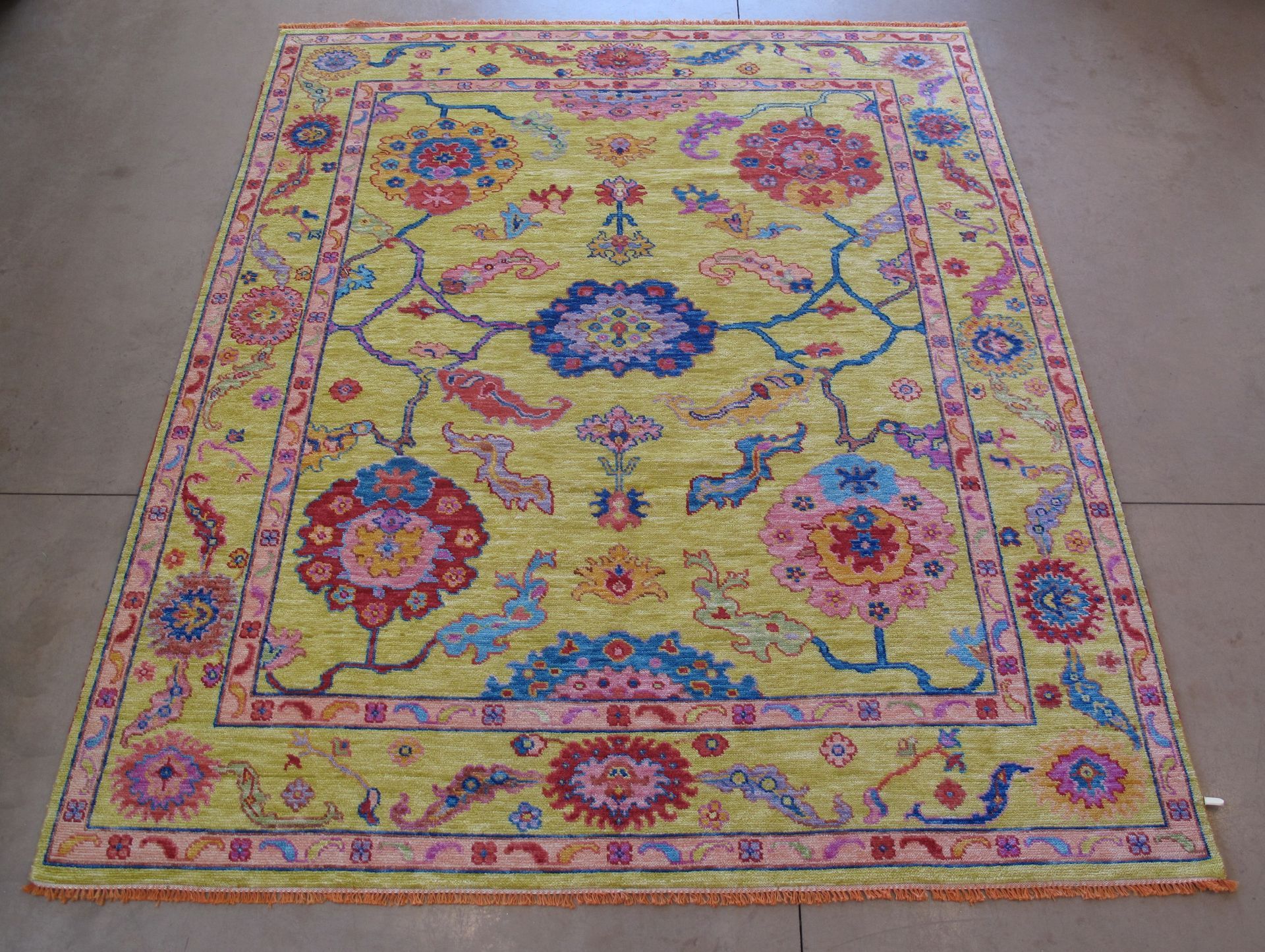 Yellow rug with floral pattern in pink, blue, and red.