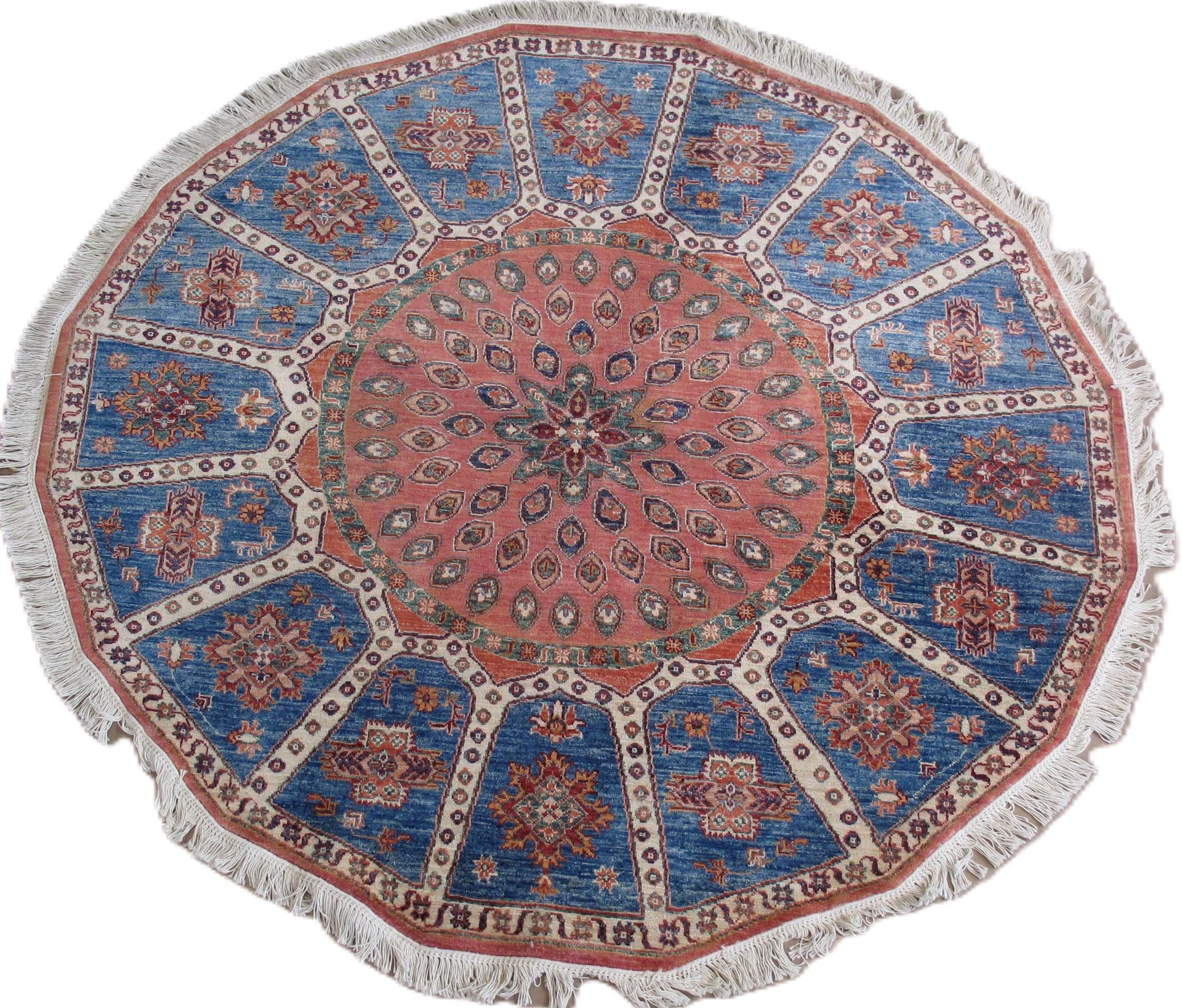 Round rug with a blue and red geometric pattern and fringe.