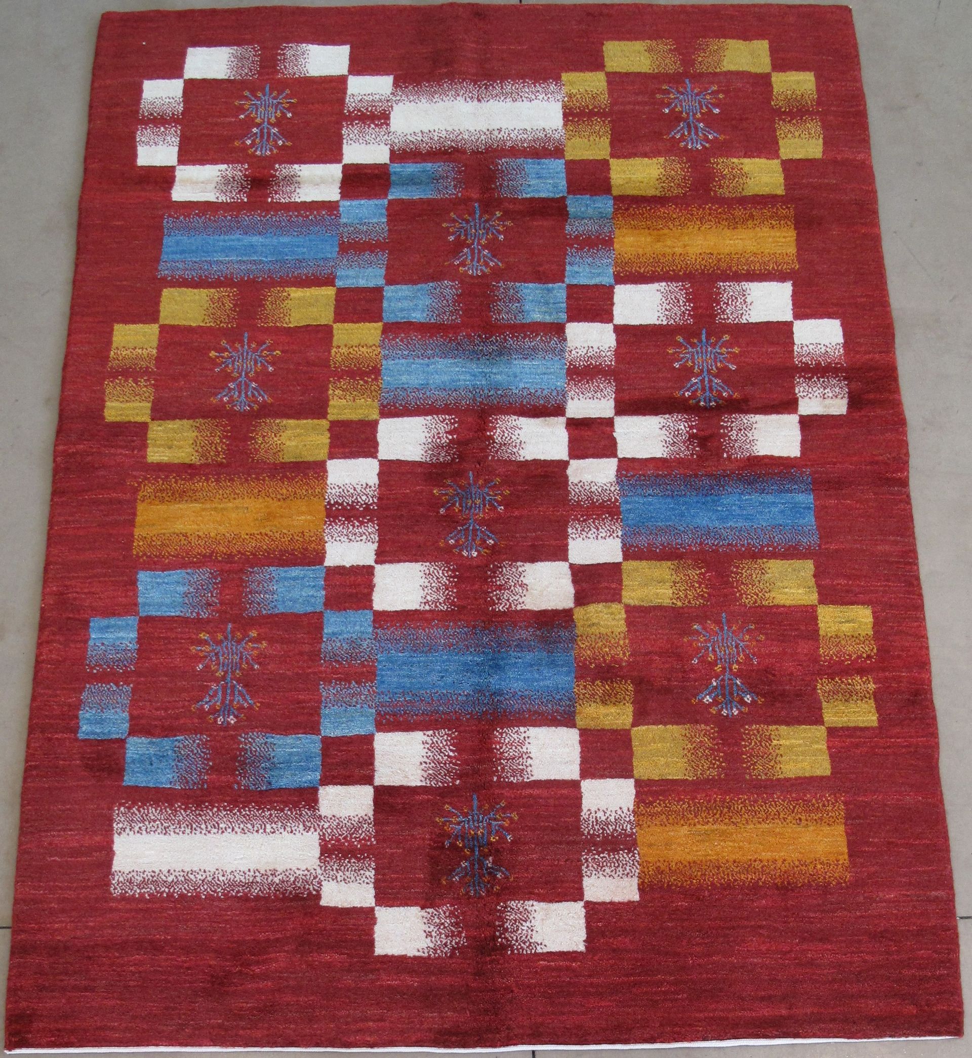 Red rug with a geometric design in blue, white, and yellow squares.