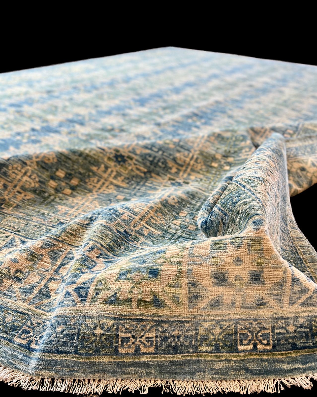 A blue and white rug with a pattern on it is on a black background.