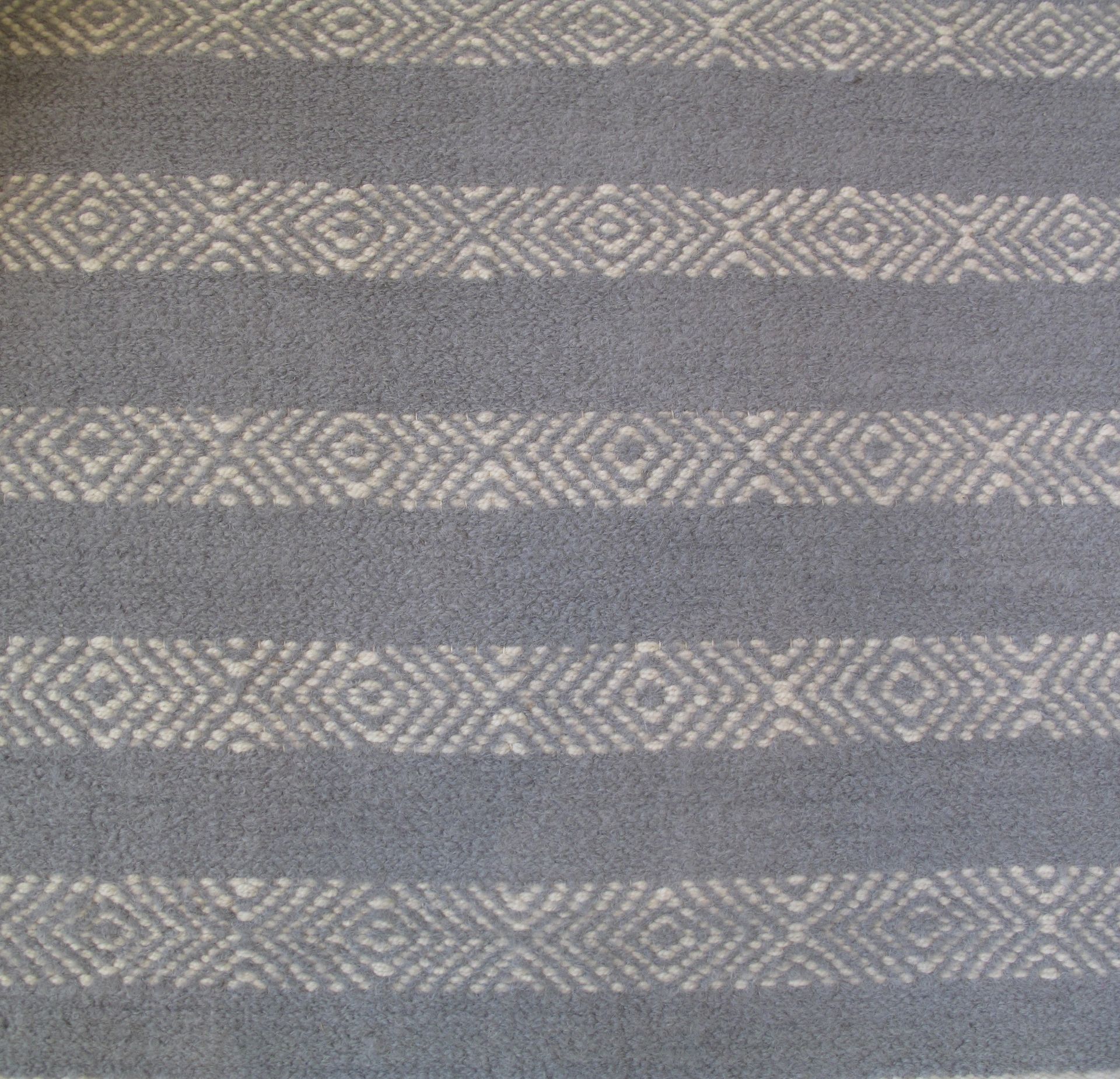 Gray woven fabric with horizontal bands of geometric diamond pattern