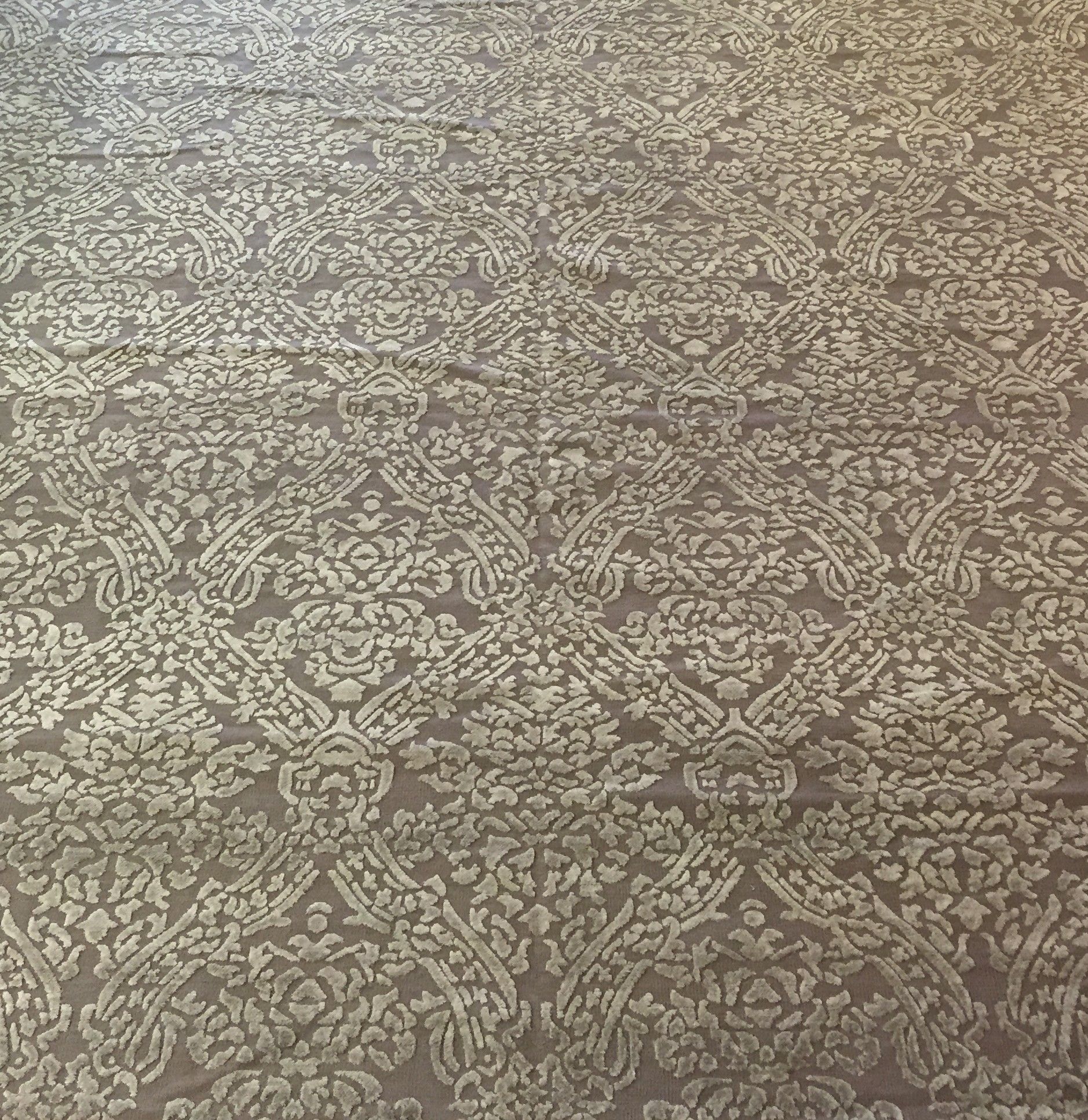 Patterned beige carpet or rug with a repeating ornate floral design