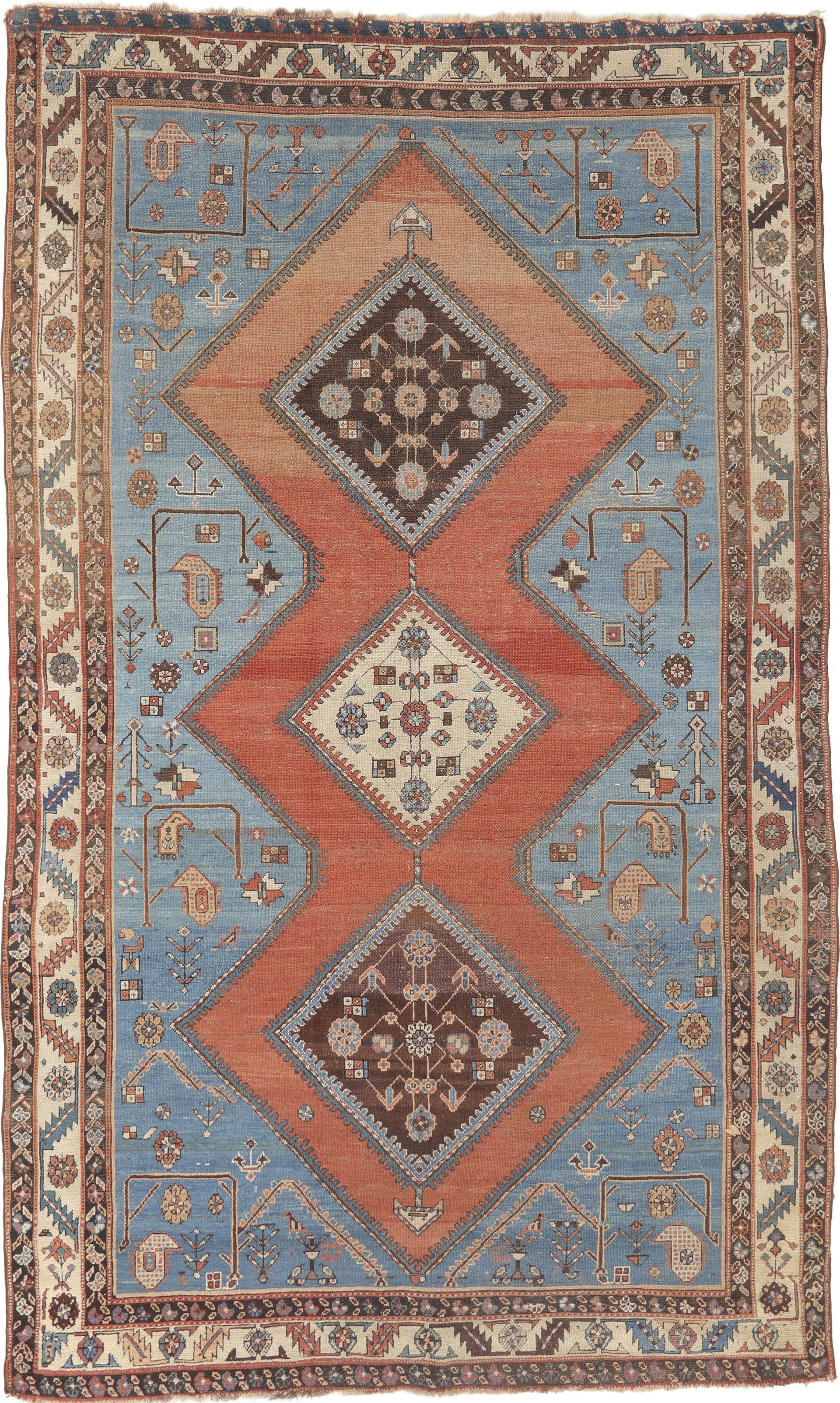 A blue and red rug with diamonds on it is on a white background.