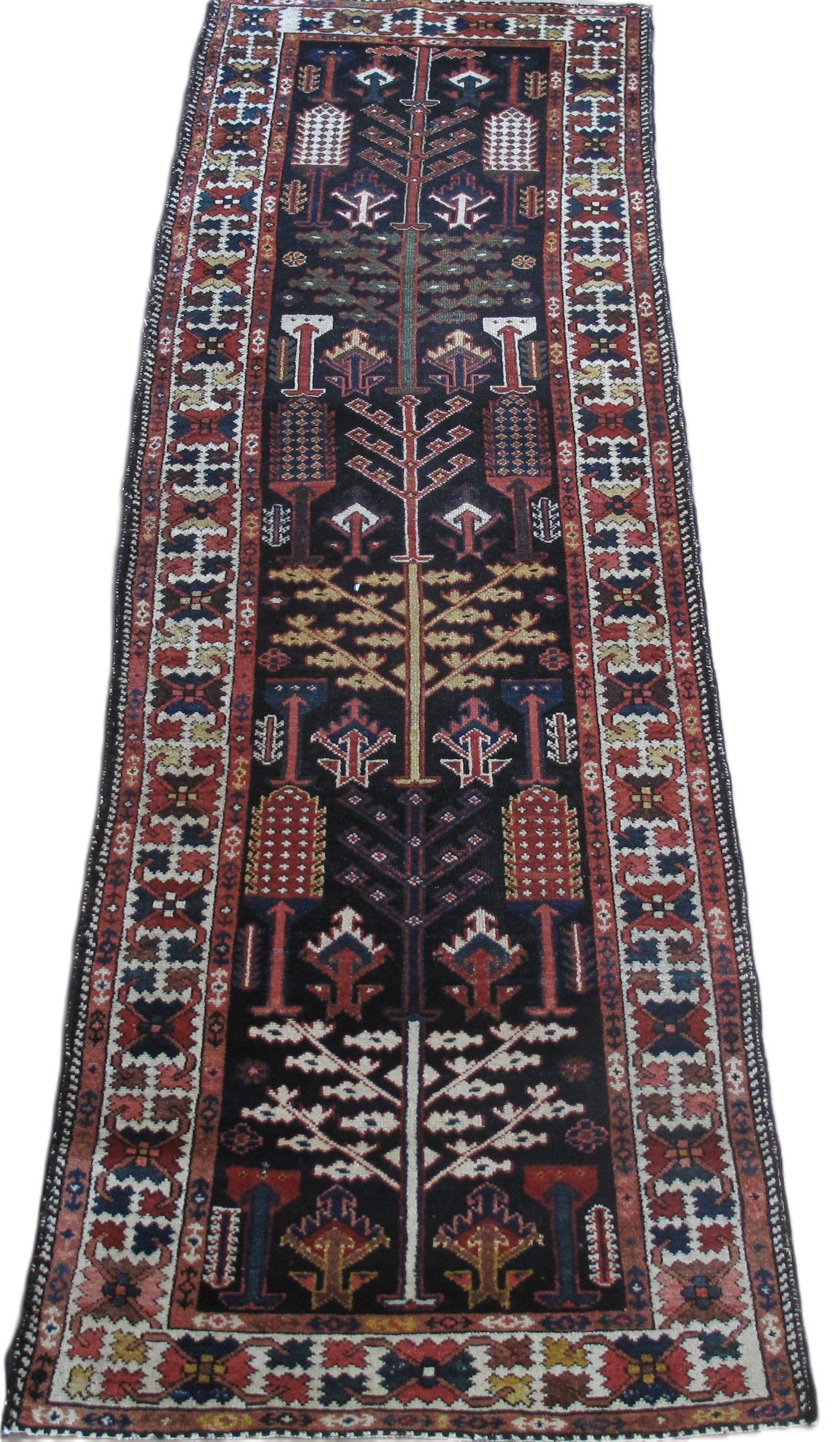 Dark rug with tree-of-life design in reds, blues, and golds against a black background.