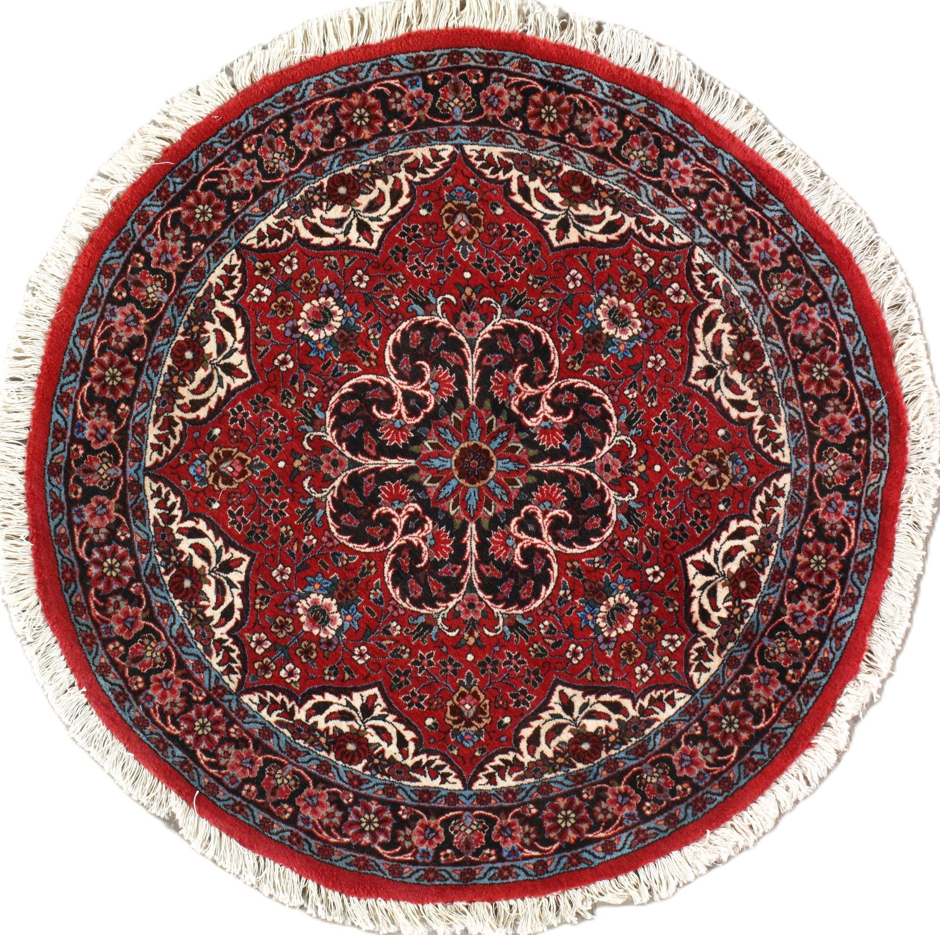 Round red Persian rug with intricate floral design and fringe.